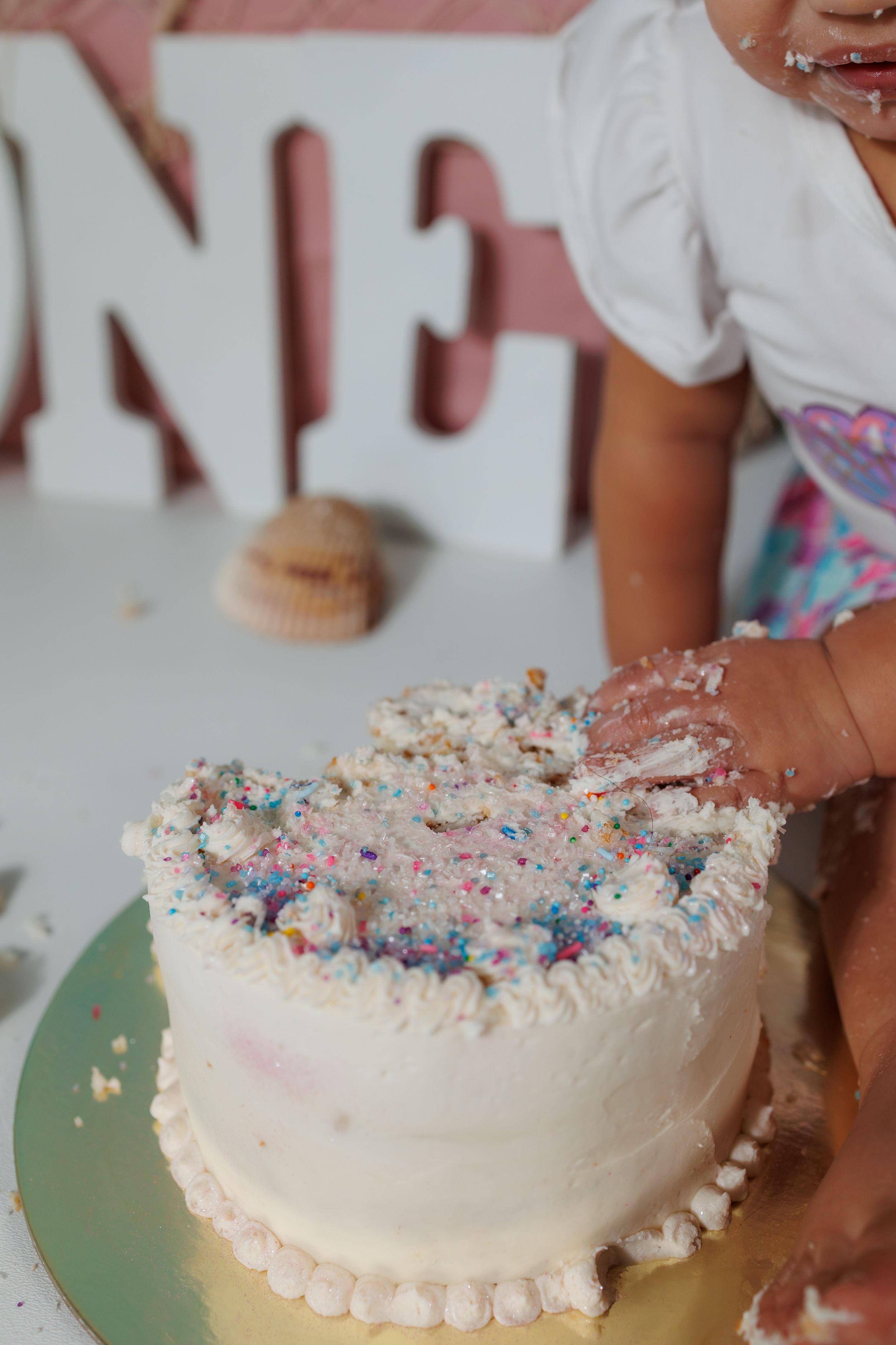 A sequence showing someone decorating a white cake with colorful sprinkles and frosted details along the edges.