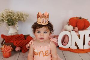 First birthday celebration setup with rose gold crown, pumpkins and floral decorations in autumn theme.