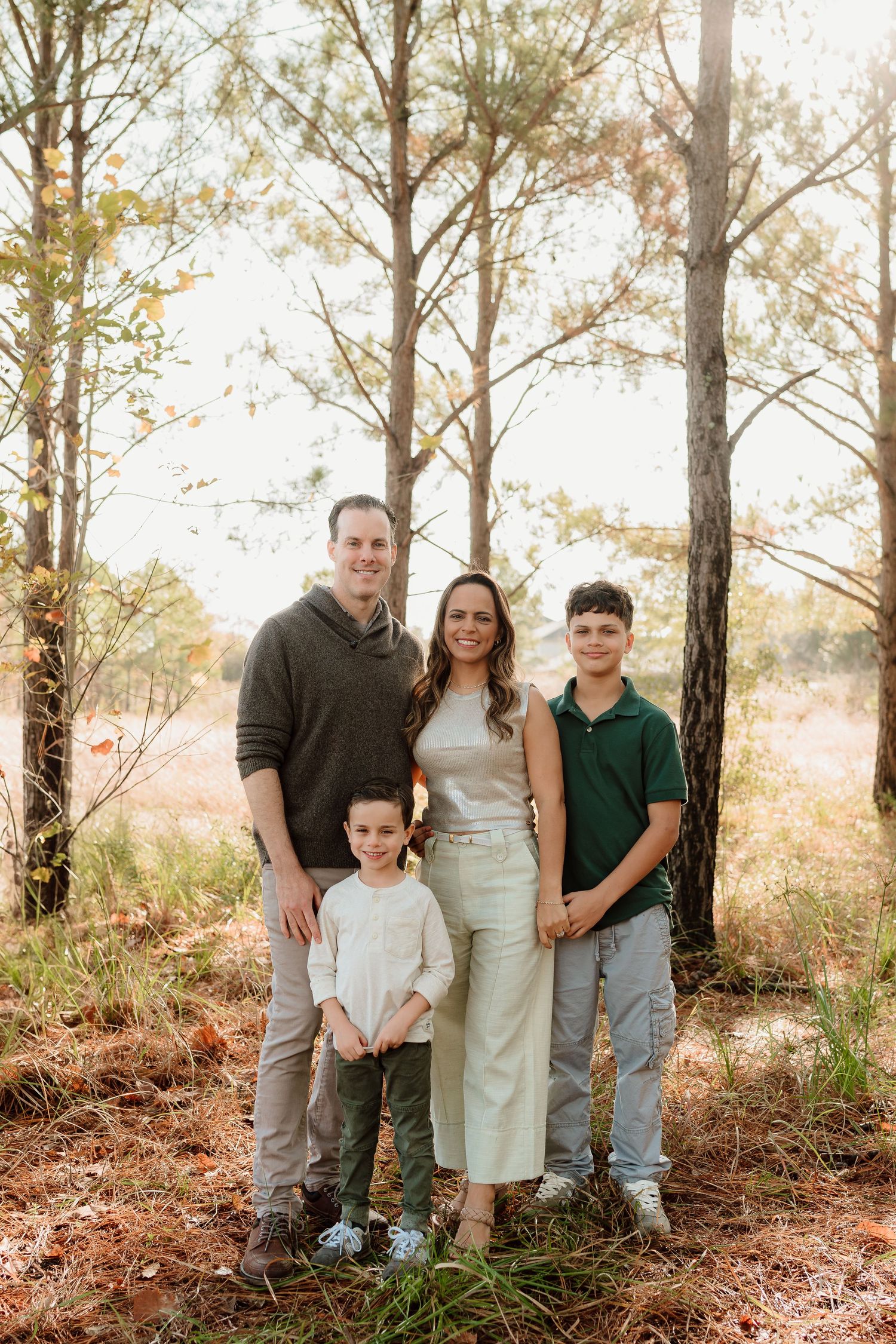 Family portrait in a pine forest with natural lighting and earth-toned clothing.