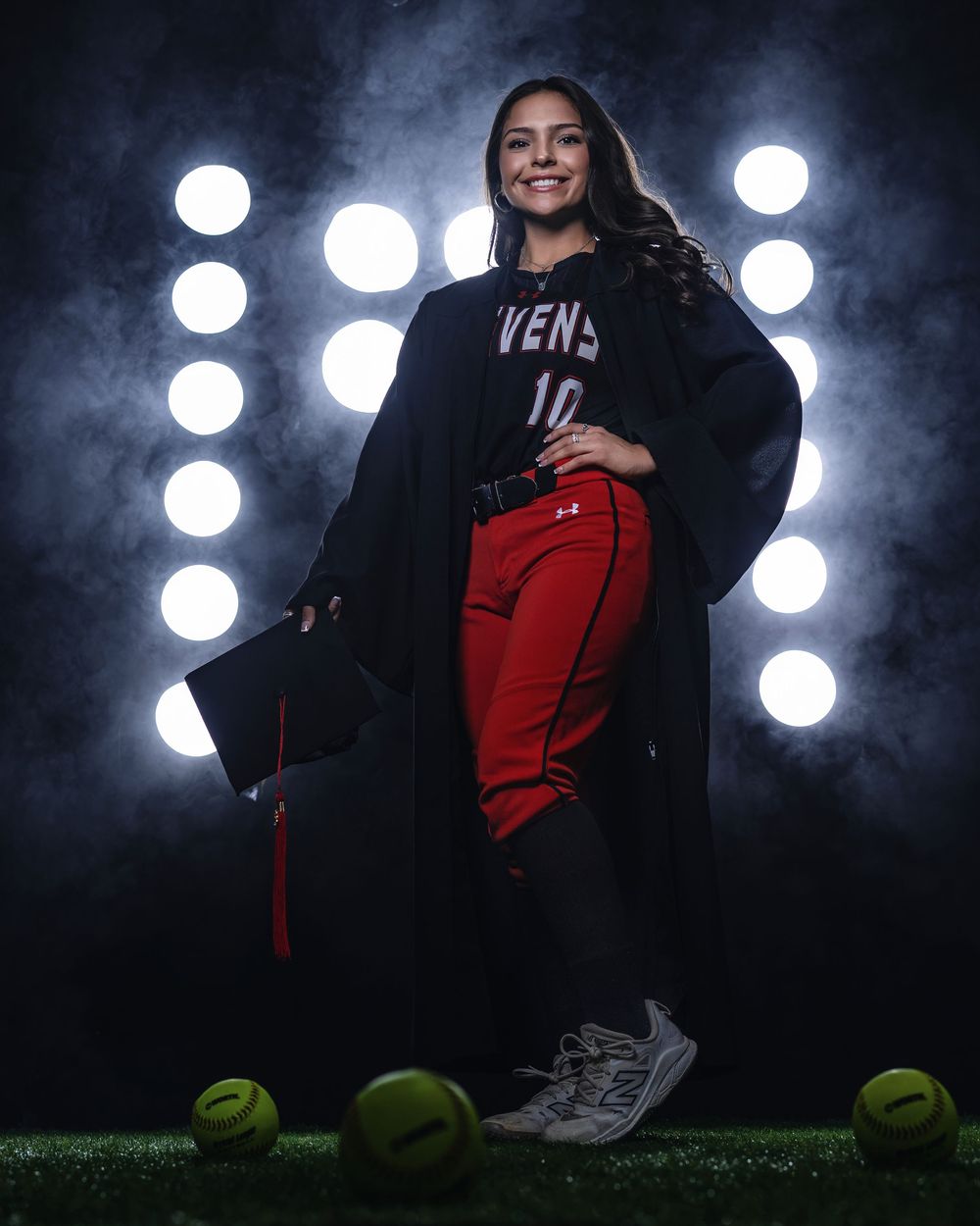 A softball athlete in red pants stands confidently with equipment against illuminated white circles.