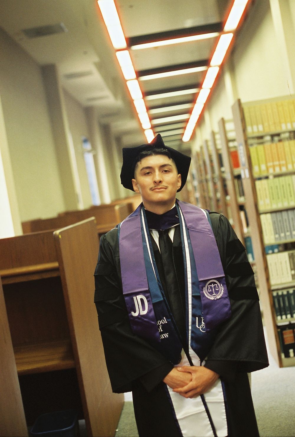 A young man poses in a library