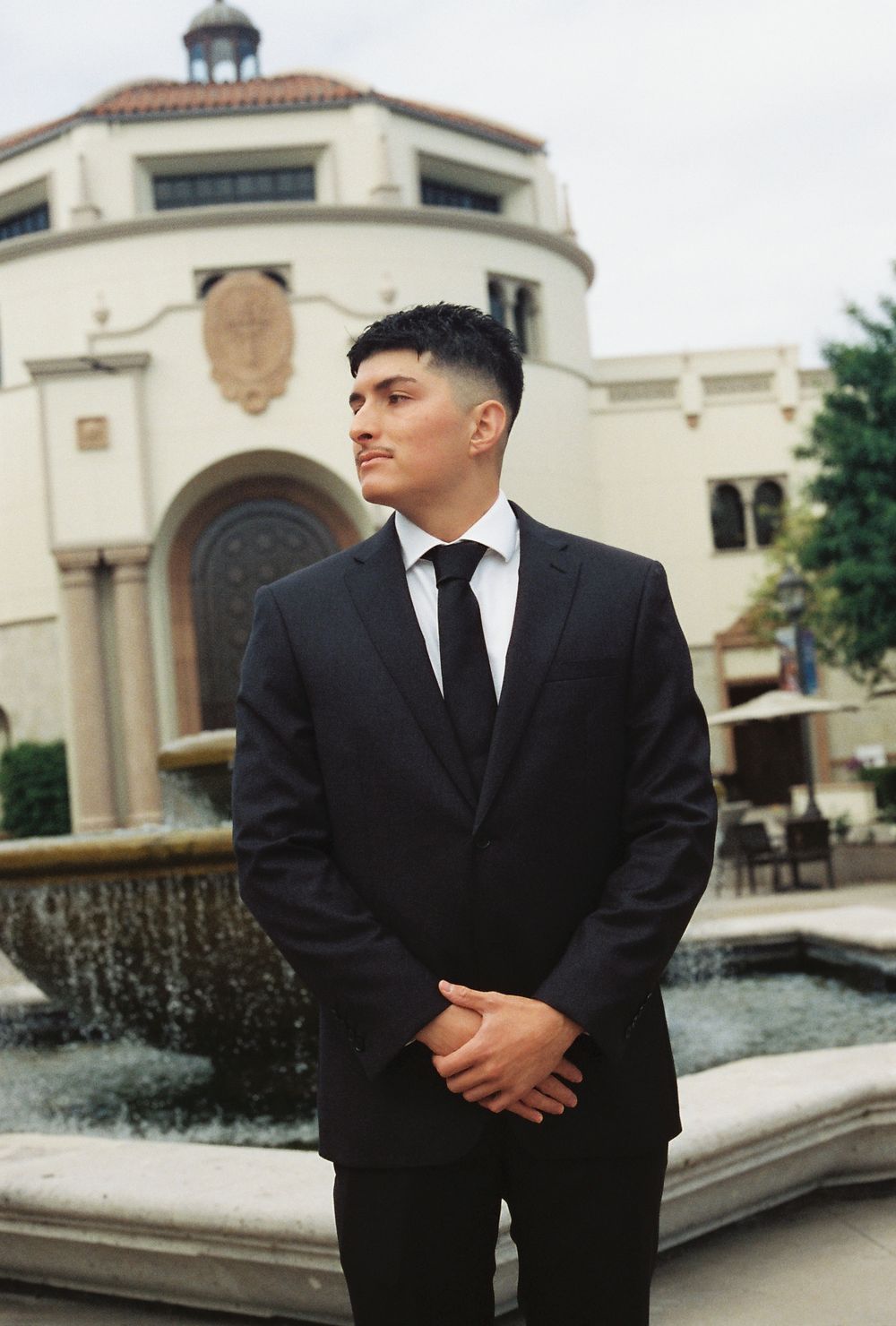 A young man poses looking away from the camera with a beautiful background