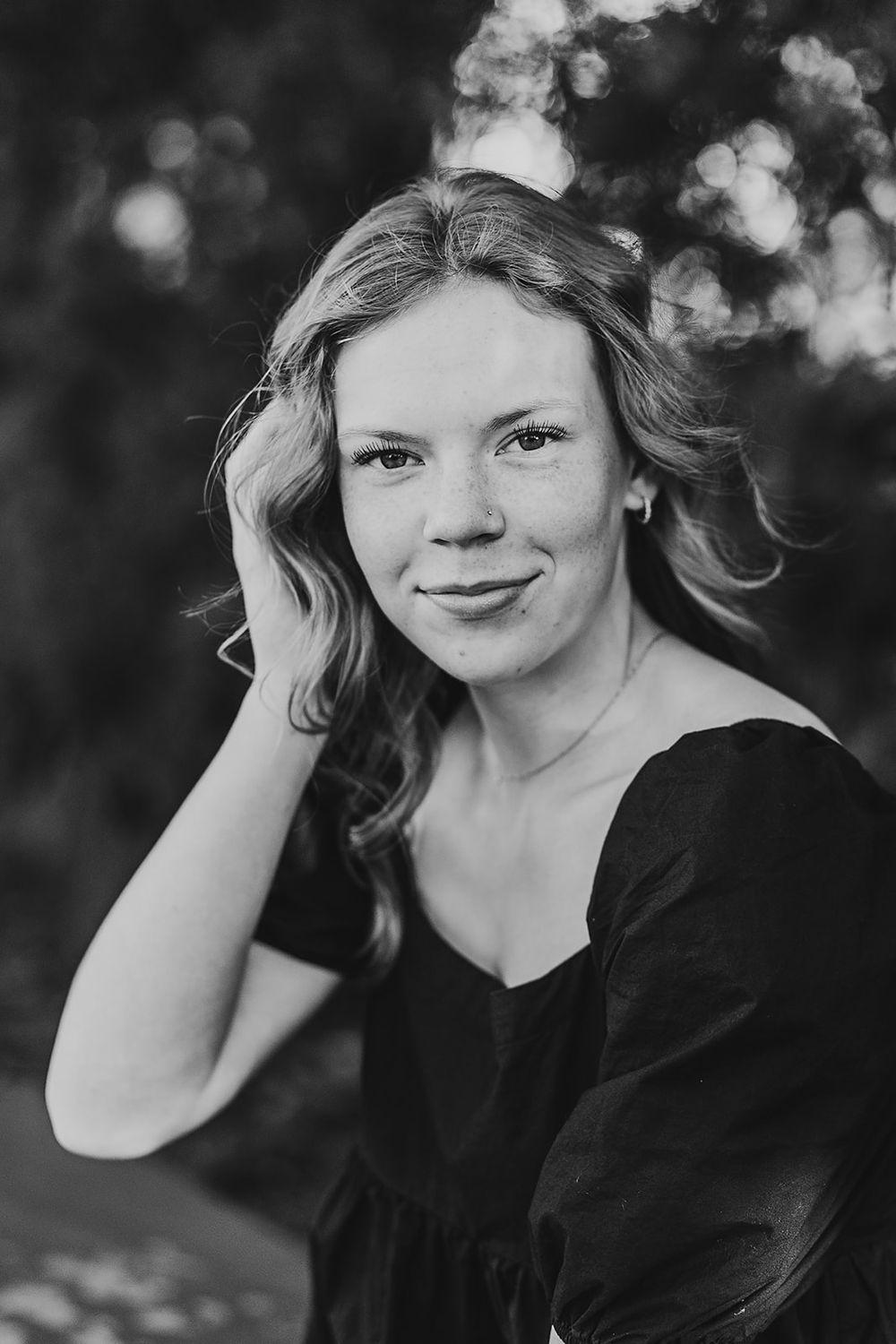 Black and white close-up portrait showing a person with wavy hair and gentle smile wearing a black top.