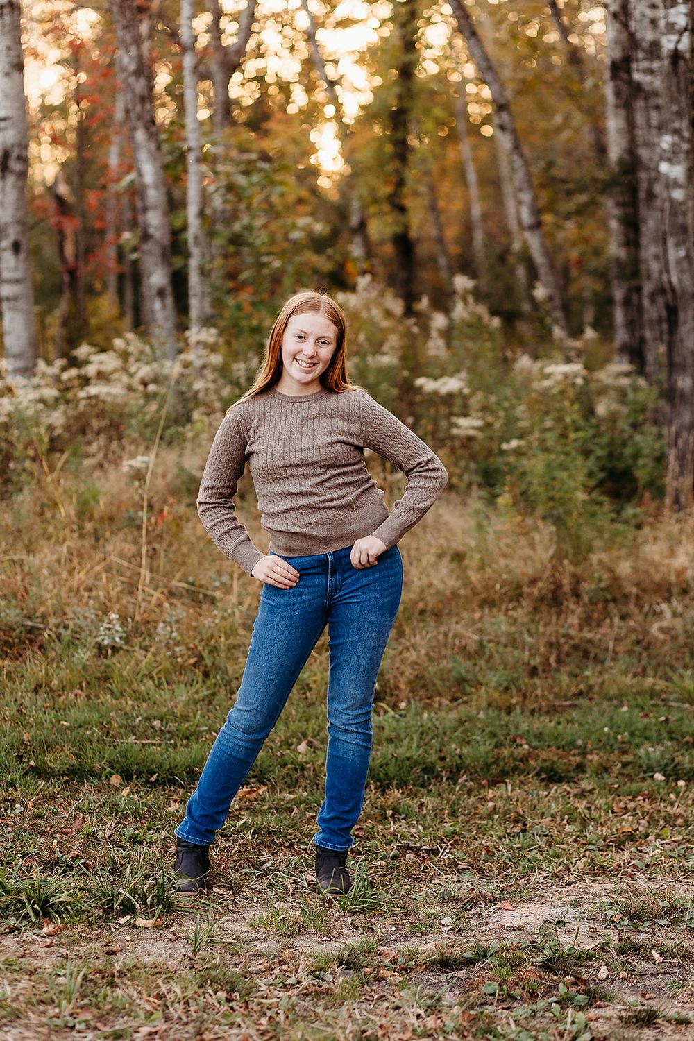 Casual fall portrait in a birch forest with warm sunlight filtered through autumn leaves.