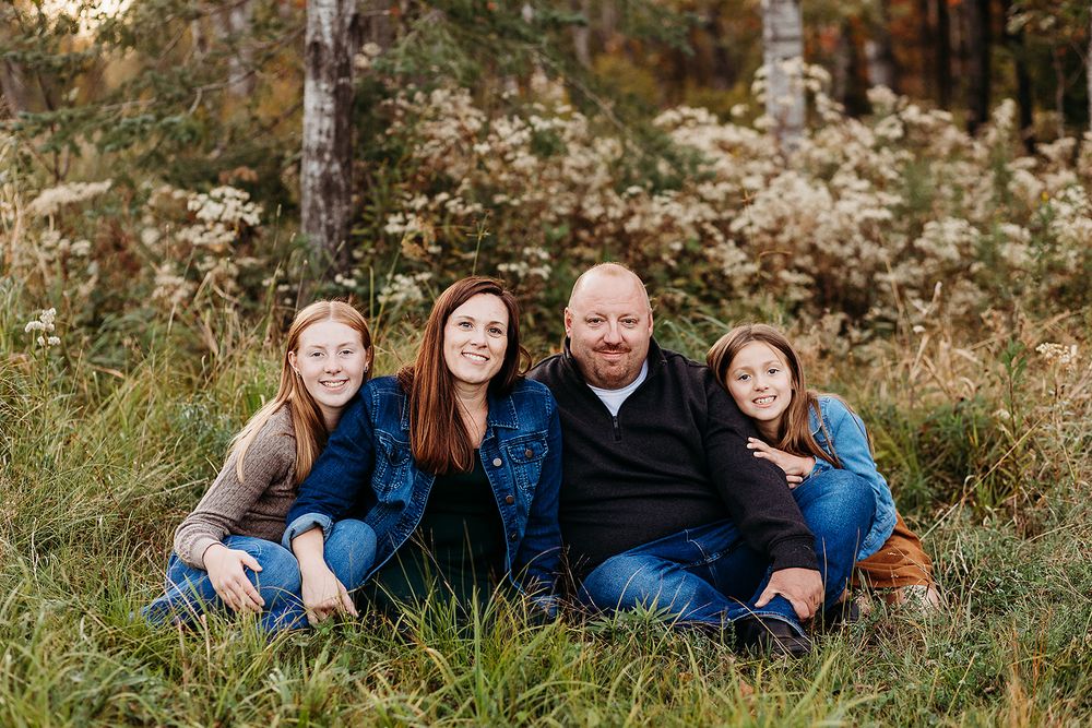 A group sits together outdoors in a natural setting with wildflowers and tall grasses during autumn.