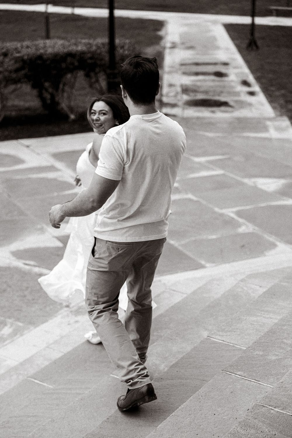 A black and white photo of someone enjoying themselves on a paved walkway on a sunny day.