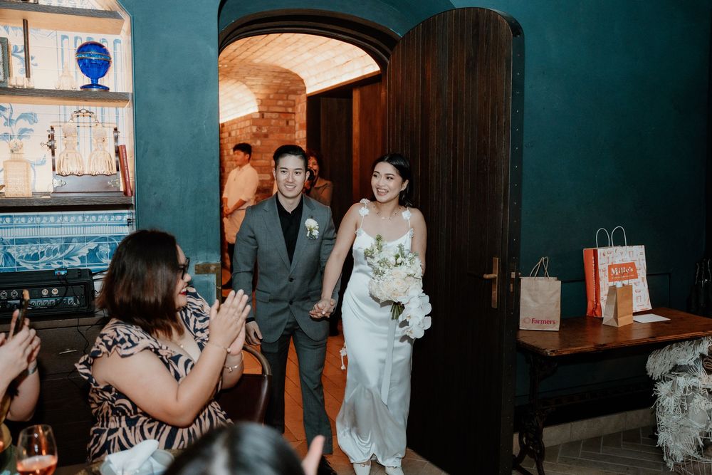 Two guests make their entrance through an arched doorway at a wedding reception venue with teal walls.