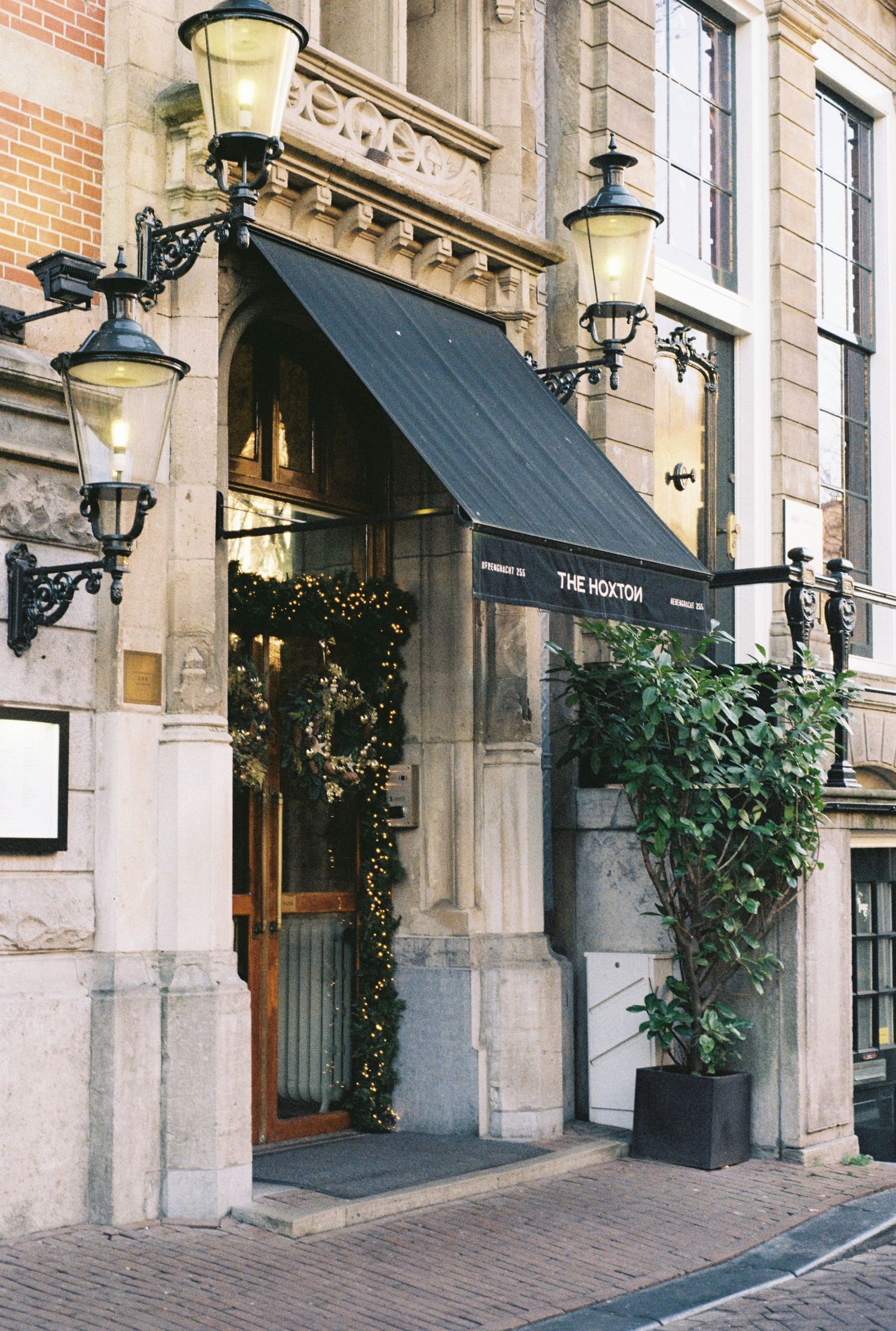 Elegant storefront entrance with decorative lanterns and climbing vines on stone facade.
