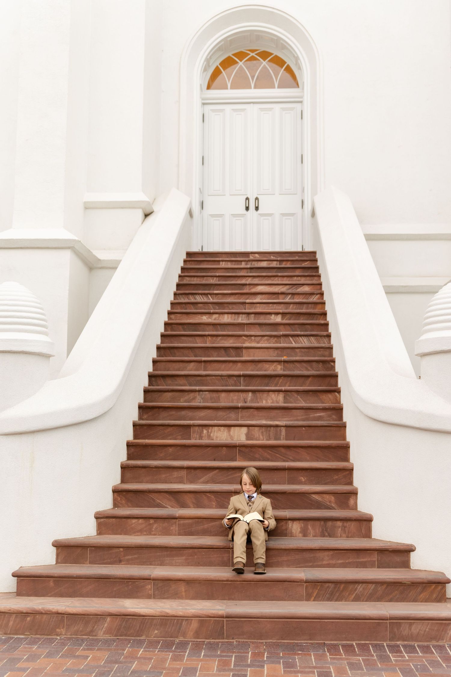 8 year old boy reading scriptures on a long staircase at the temple