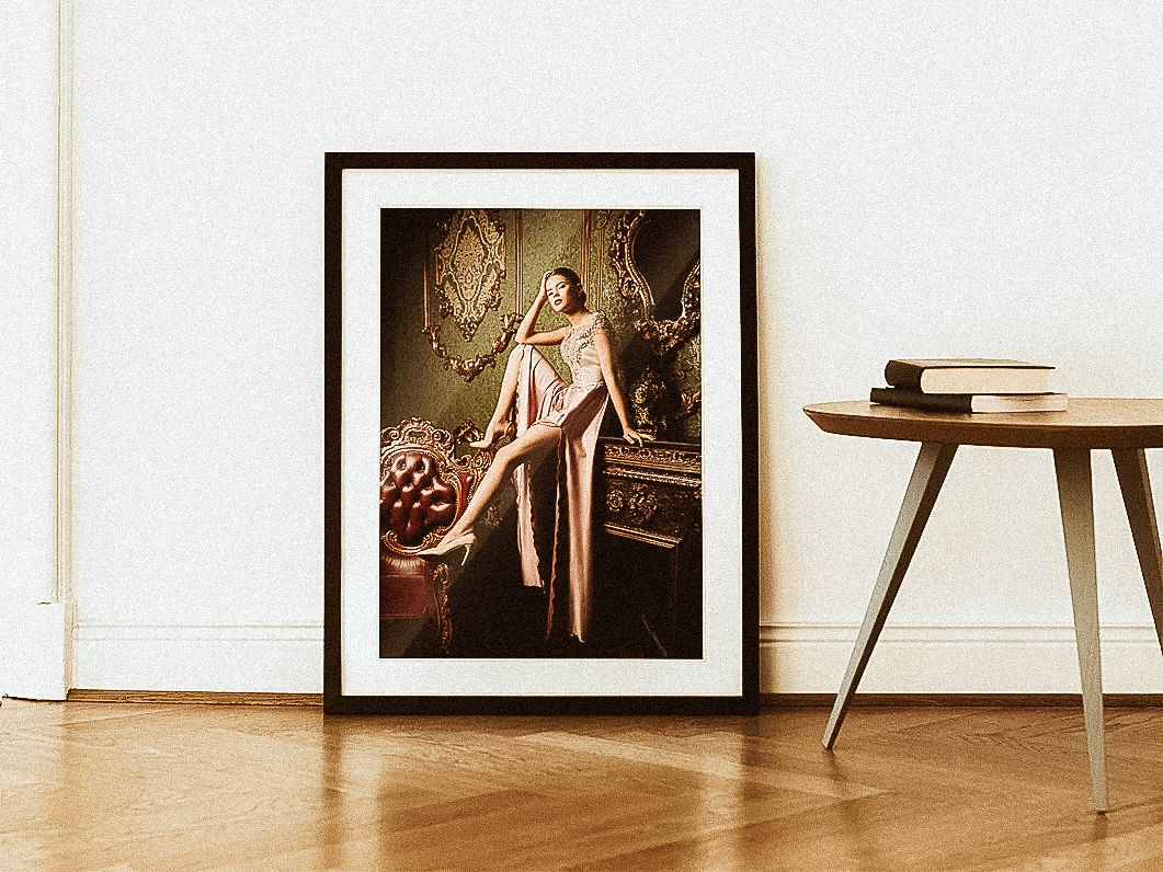 Framed vintage-style portrait in sepia tones displayed beside a wooden side table with stacked books.