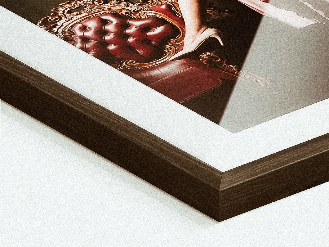 Close-up detail of a framed photograph showing the corner of a brown wooden frame against a white border.