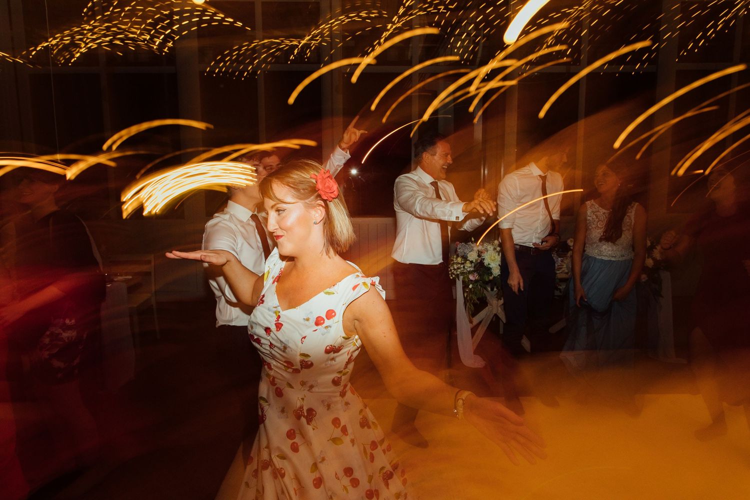People dancing at a wedding reception with motion blur and warm lighting effects creates a dynamic party atmosphere.