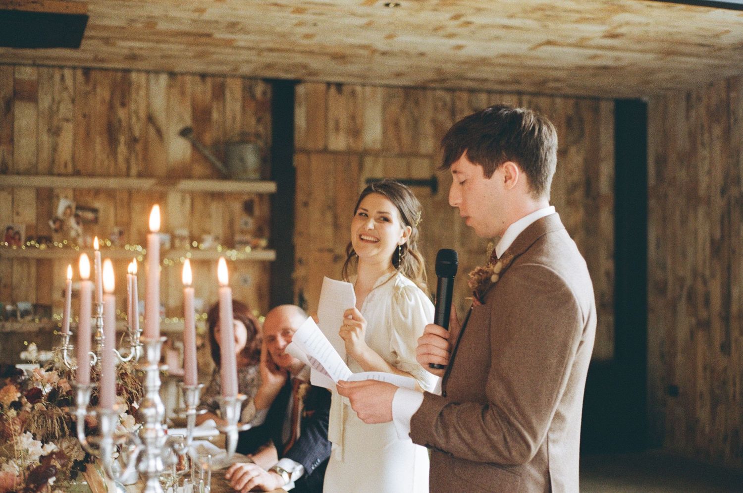 A couple sharing a joyful moment together at a candlelit reception with elegant white tapered candles in crystal holders.