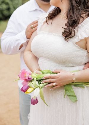 A close-up photo shows someone in a white dress holding colorful tulips while standing outdoors.
