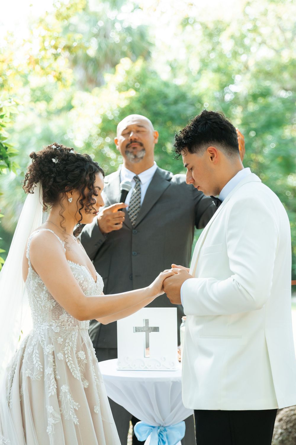 An intimate outdoor wedding ceremony with couple exchanging rings in front of an officiant by a small altar table.