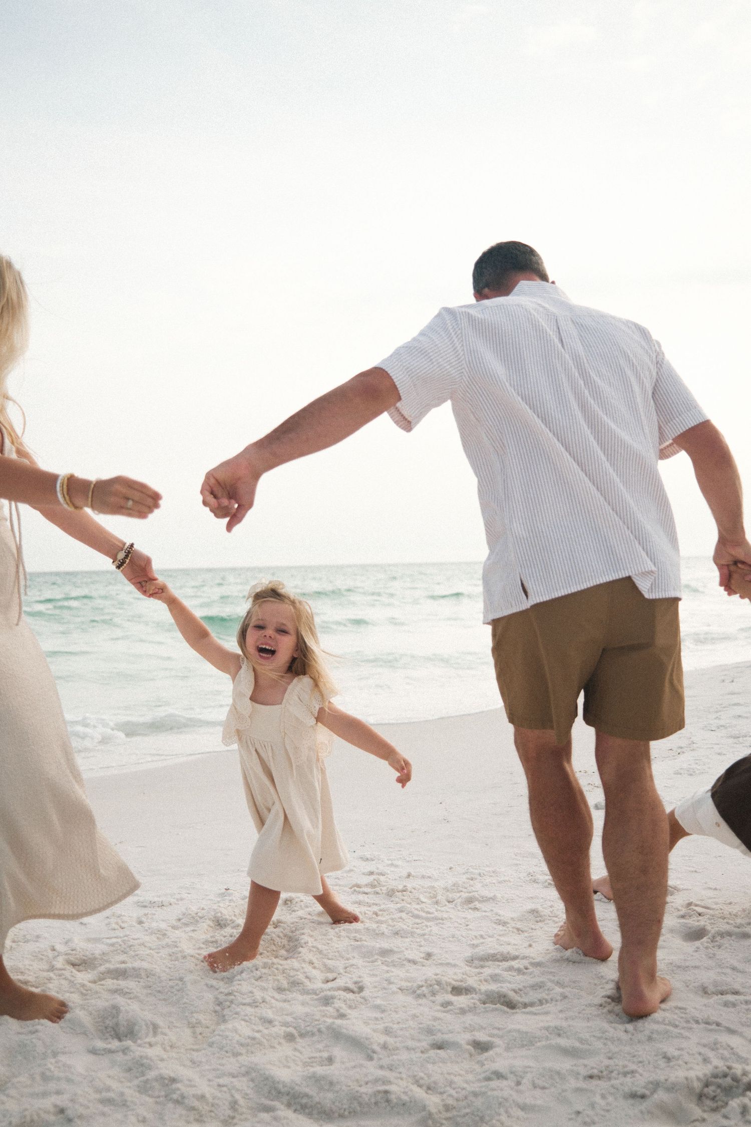 People playing and dancing together on a sandy beach at sunset.