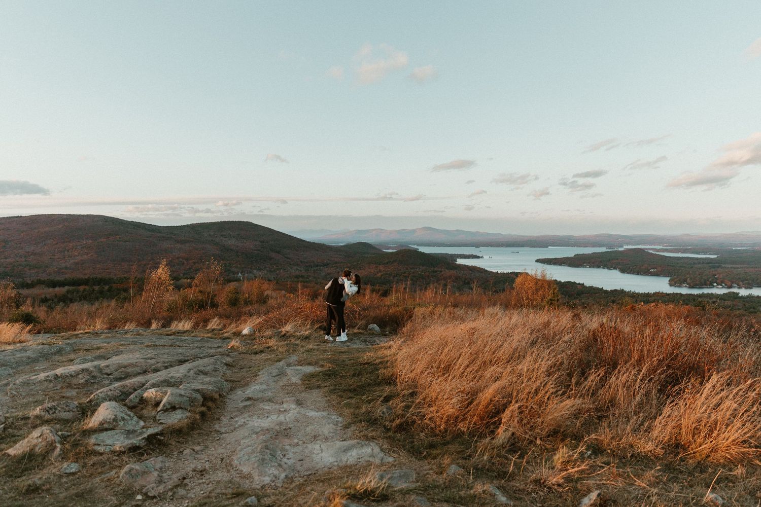 Panoramic mountain landscape view with autumn colors and water in the distance.
