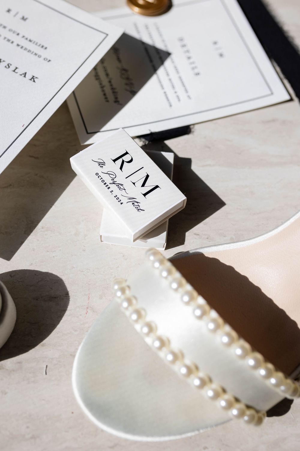Elegant white business cards and a pearl necklace in a ceramic bowl create a minimalist branding flatlay.