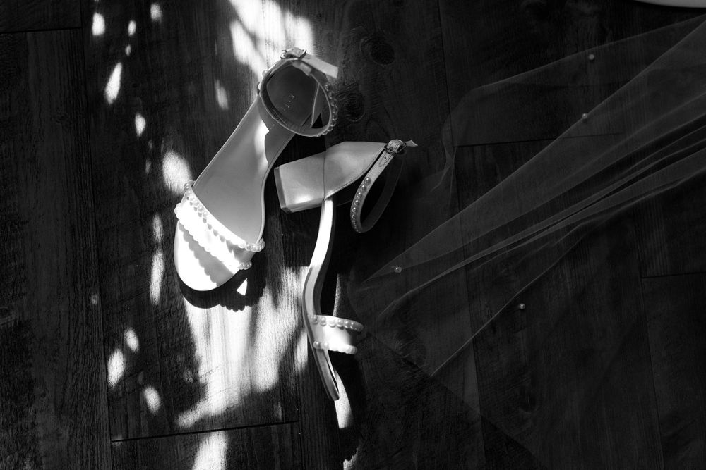 A black and white photograph shows dramatic light and shadow patterns falling through blinds onto a wall.