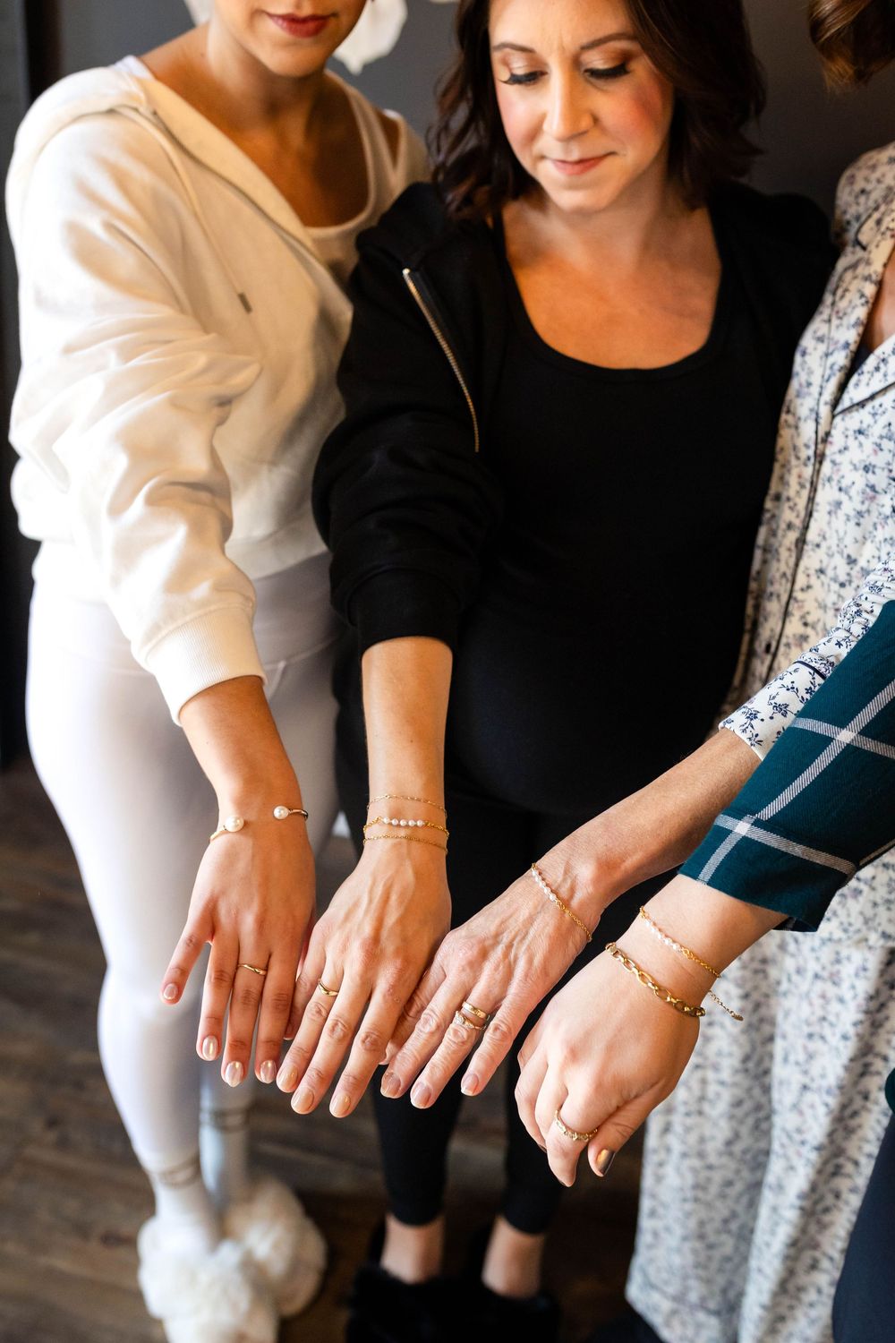 Close-up shot of hands with jewelry and bracelets gathered together in a group moment.