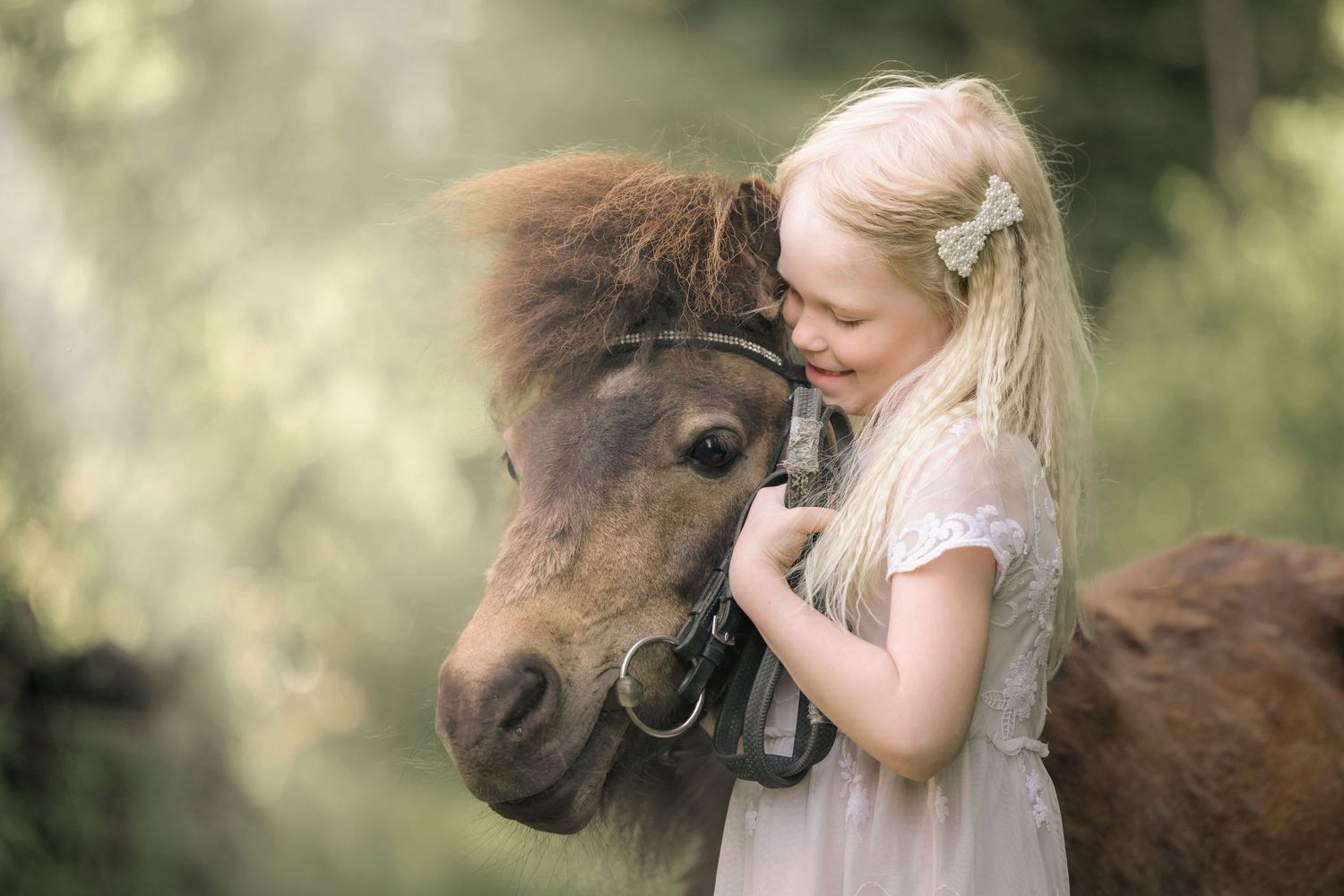 A young blonde girl in a white dress affectionately hugging a brown Shetland pony outdoors.