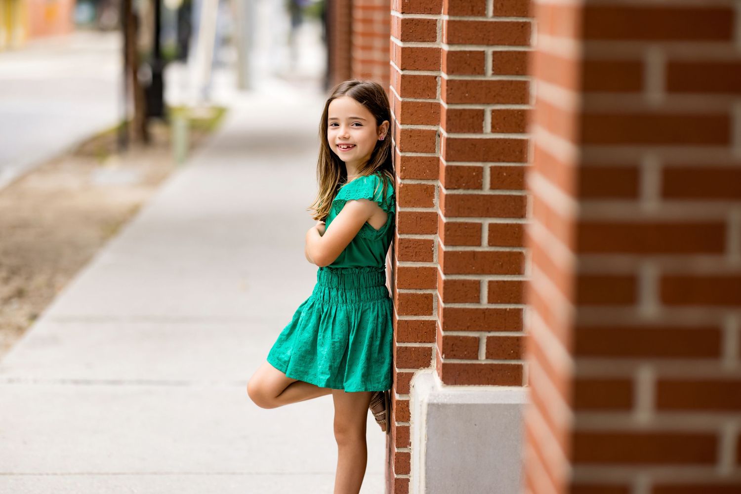 Brick wall backdrop with children dressed in colorful summer outfits during outdoor photoshoot.