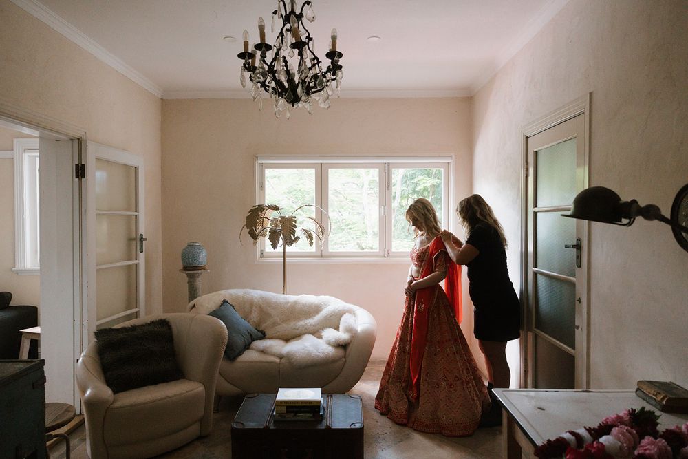 Two figures standing in a bright, elegant living room with a vintage chandelier and cream sofa.