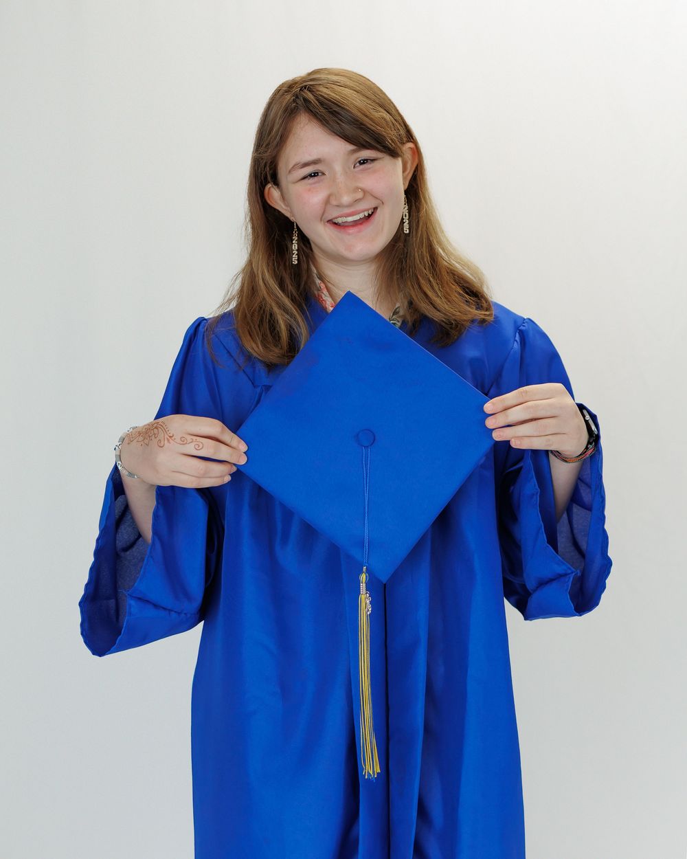 Series showing bright blue graduation cap and gown being held and displayed against white background.