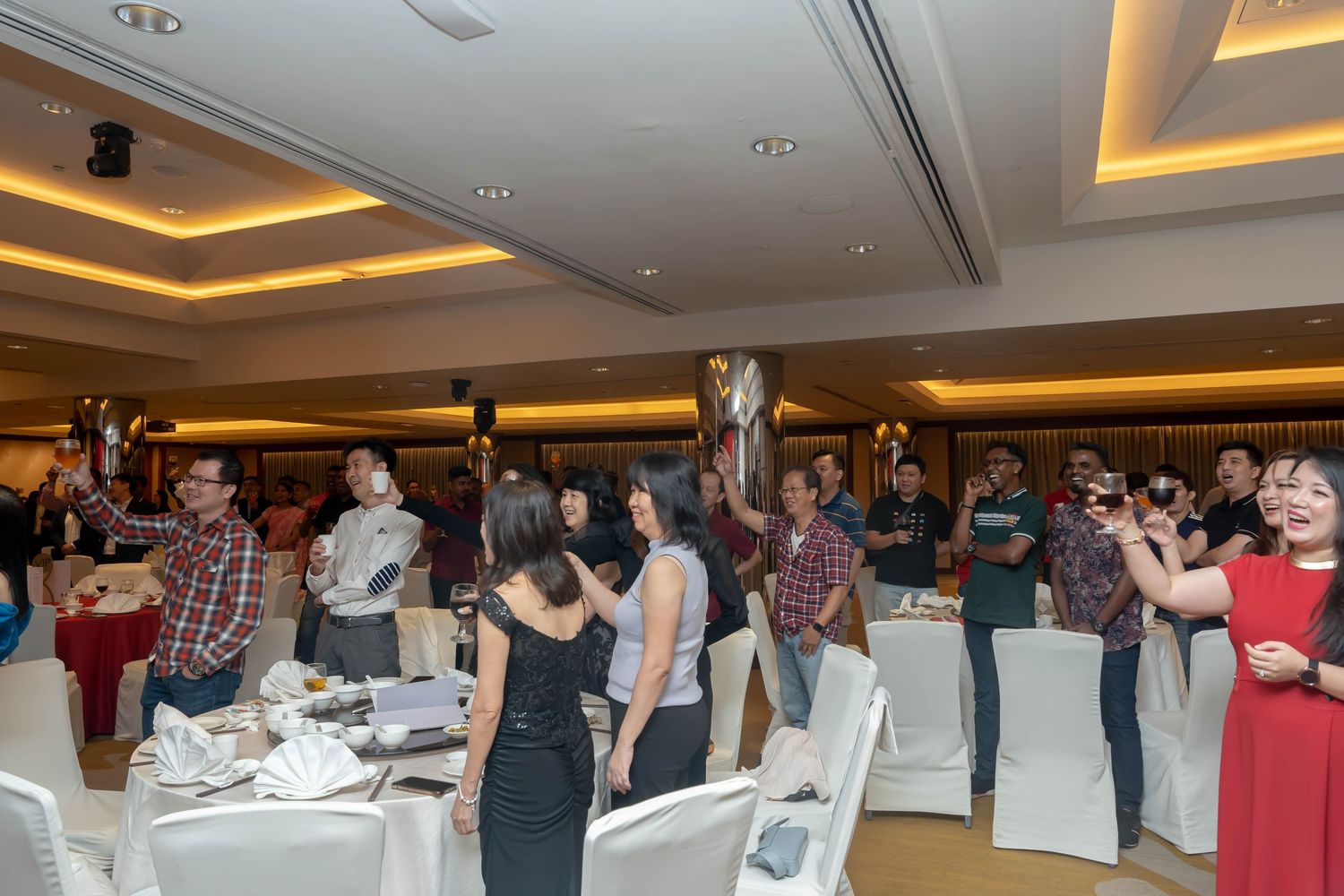 Wedding reception venue with guests mingling and dancing in an elegantly lit banquet hall.