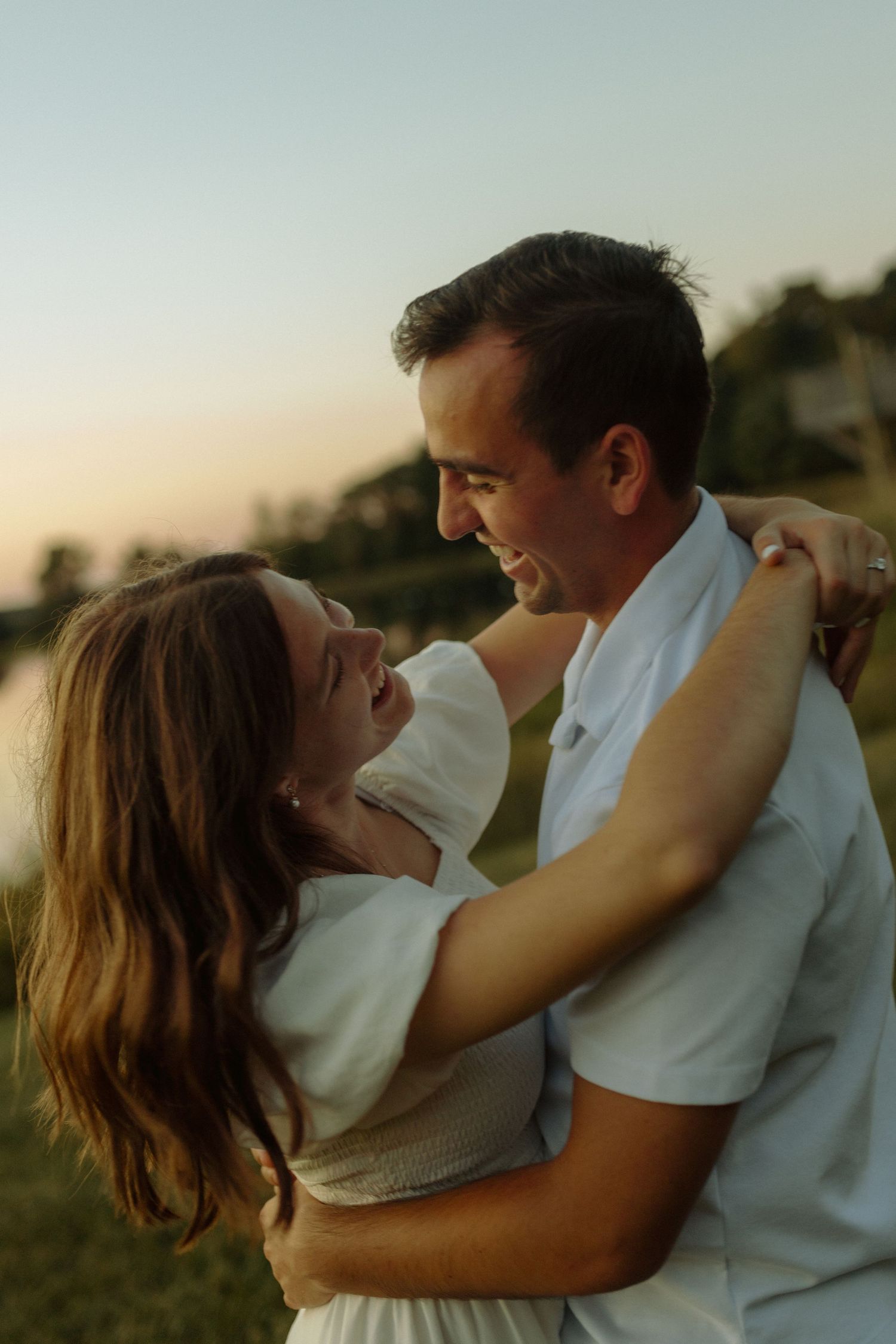 Couple sharing tender moments in casual attire against natural outdoor backdrop.