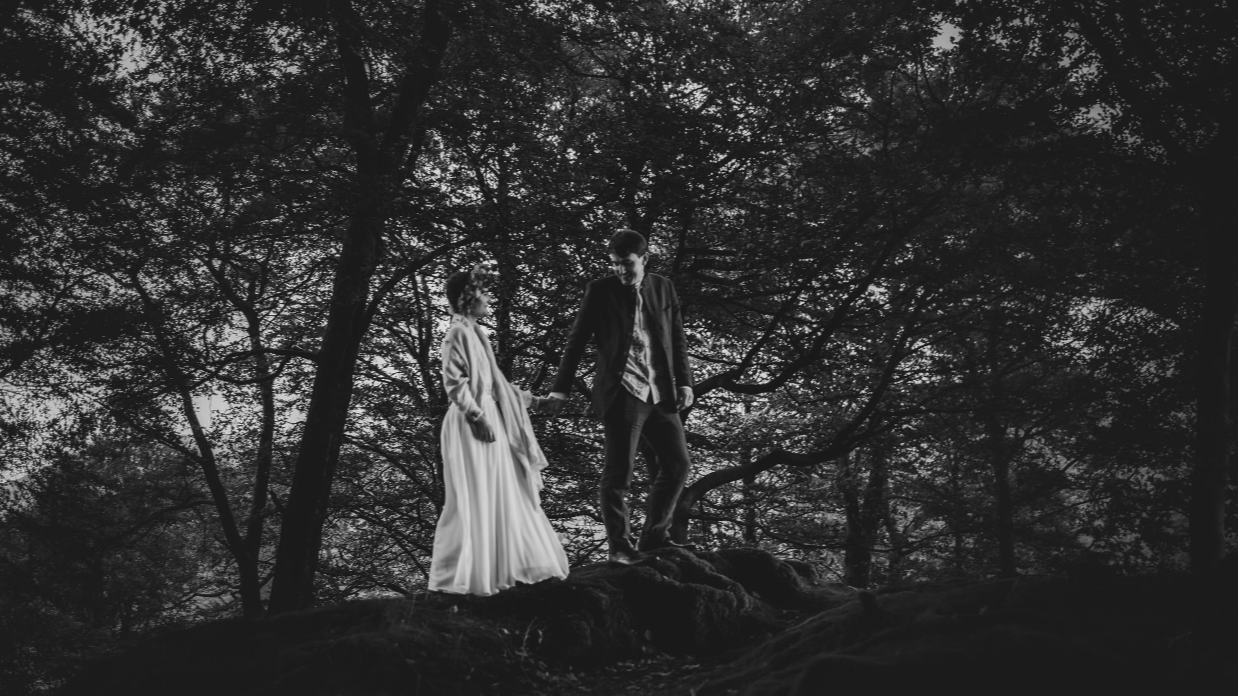 non-traditional wedding photographer in the Lake District - bride and groom walking through the forest