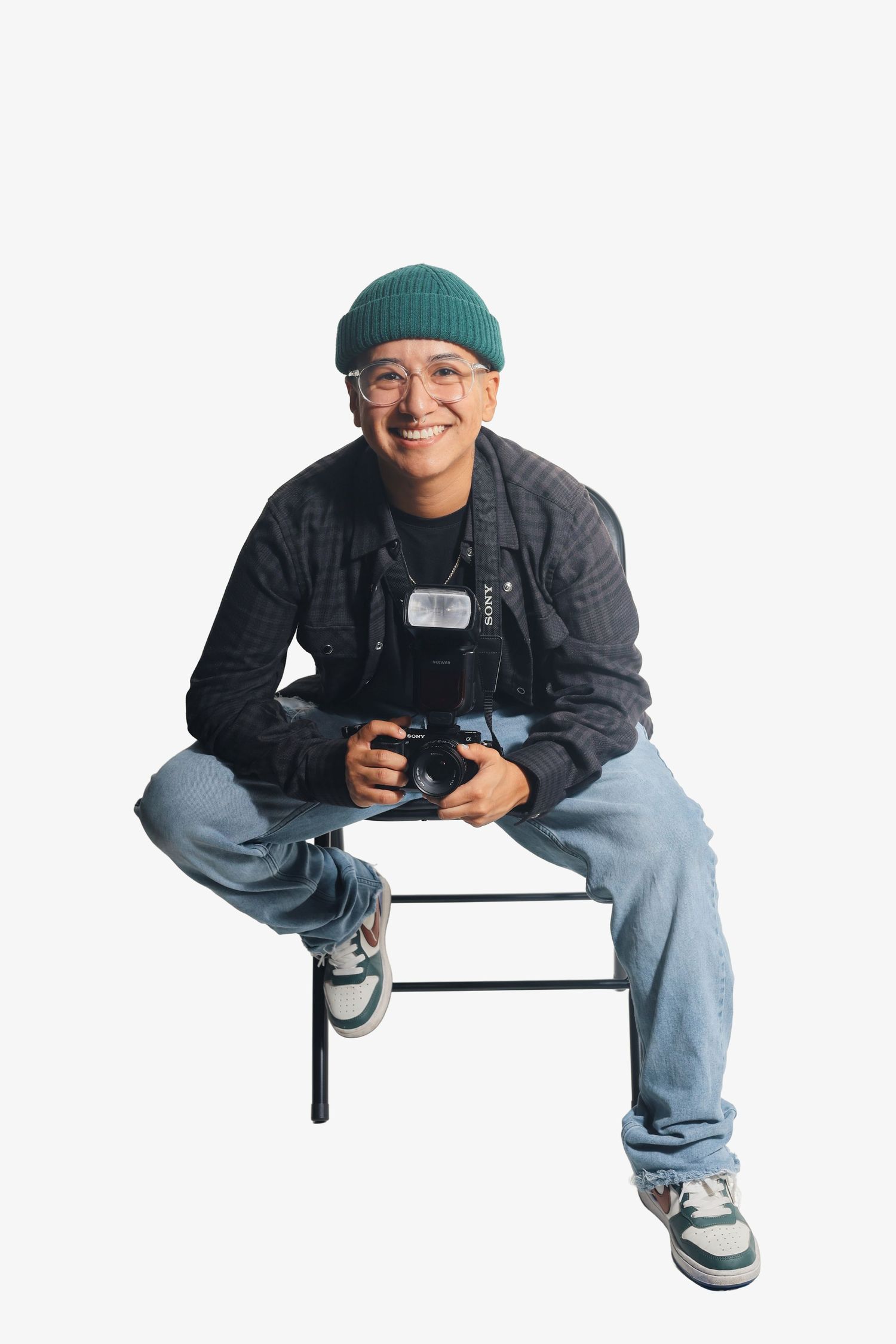 Person in casual wear and green beanie sitting on a bench against white background.