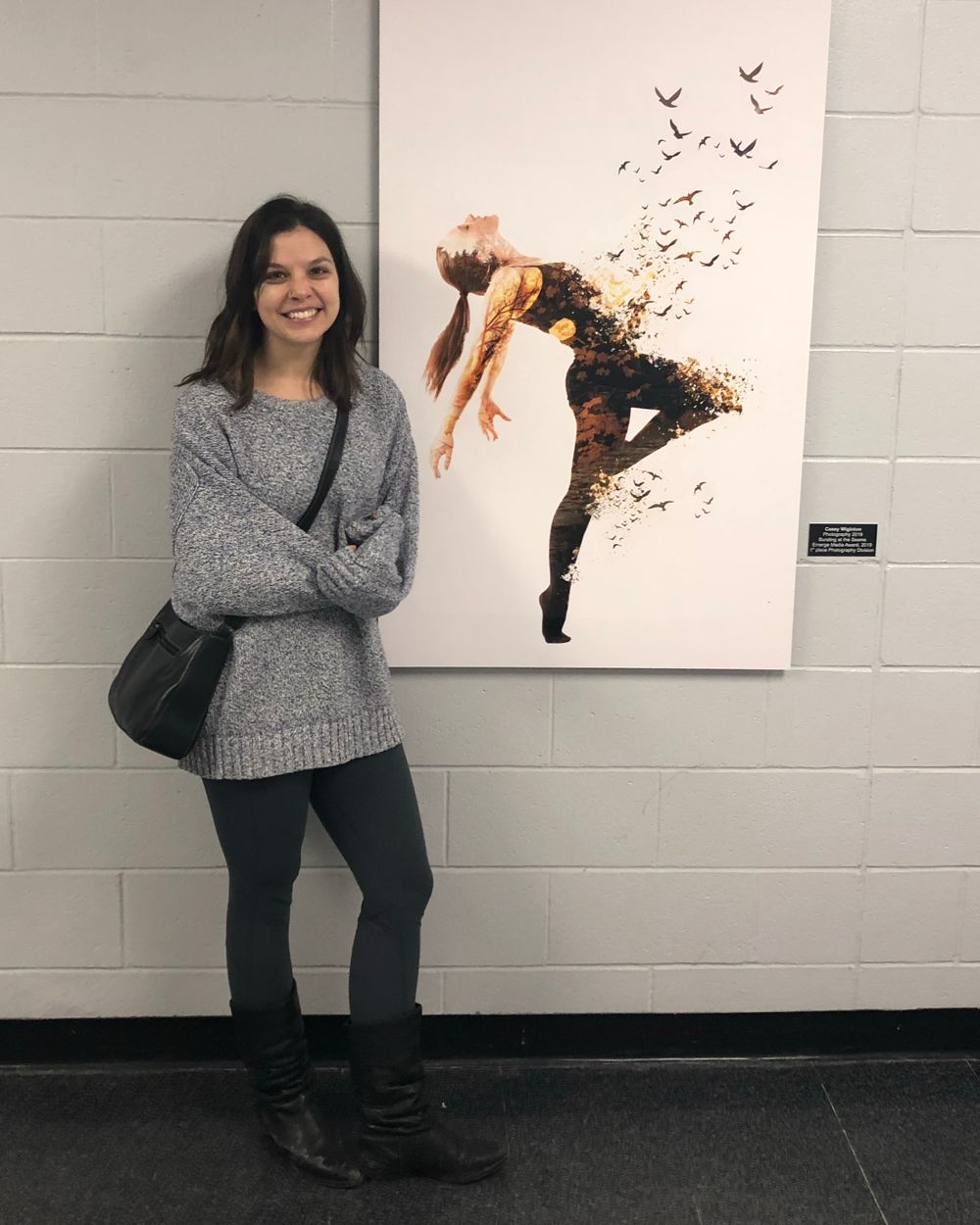 Person poses next to artistic wall art depicting a dancer dissolving into birds. This was  Casey Anne Images art purchased by Fanshawe