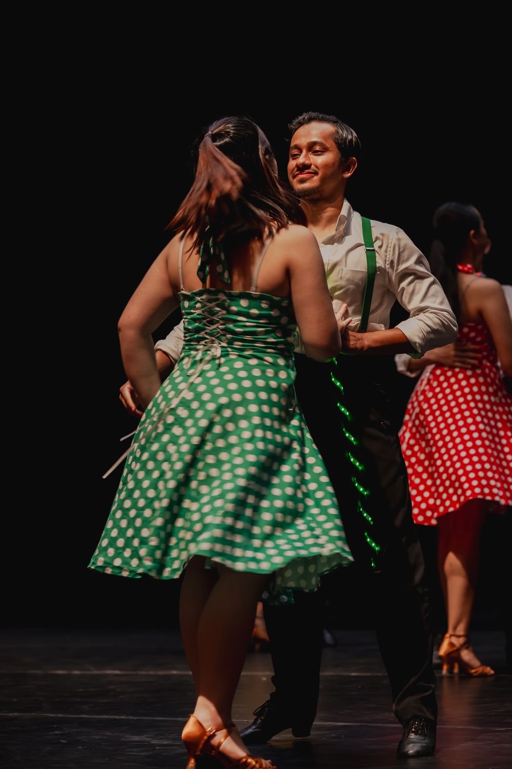 Couples dancing in vintage-style polka dot dresses during swing dance performance.
