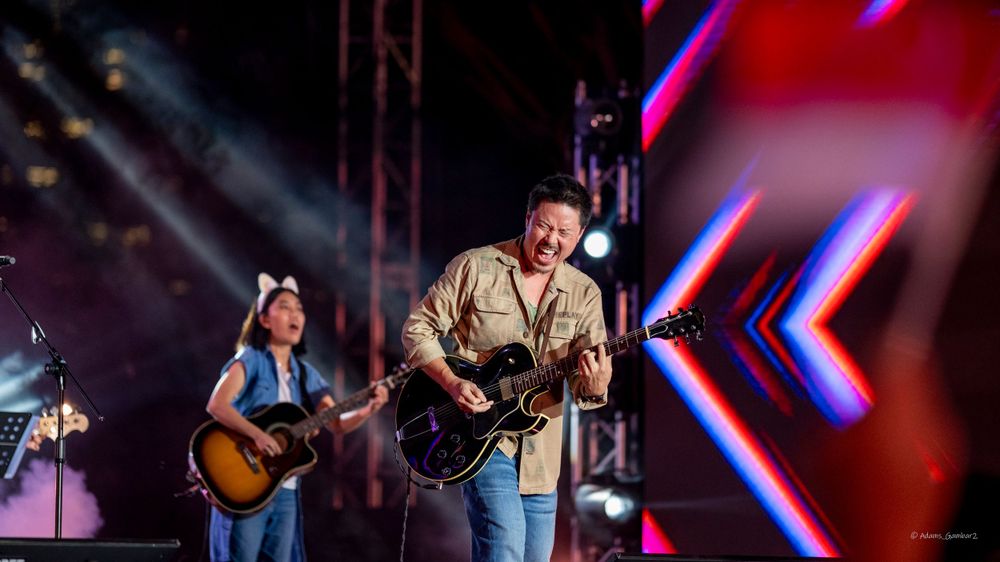 Musicians performing on concert stage with colorful lighting effects.
