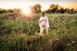 Glowing sunset illuminates a person walking through a wild flower meadow creating a dreamy summer scene.