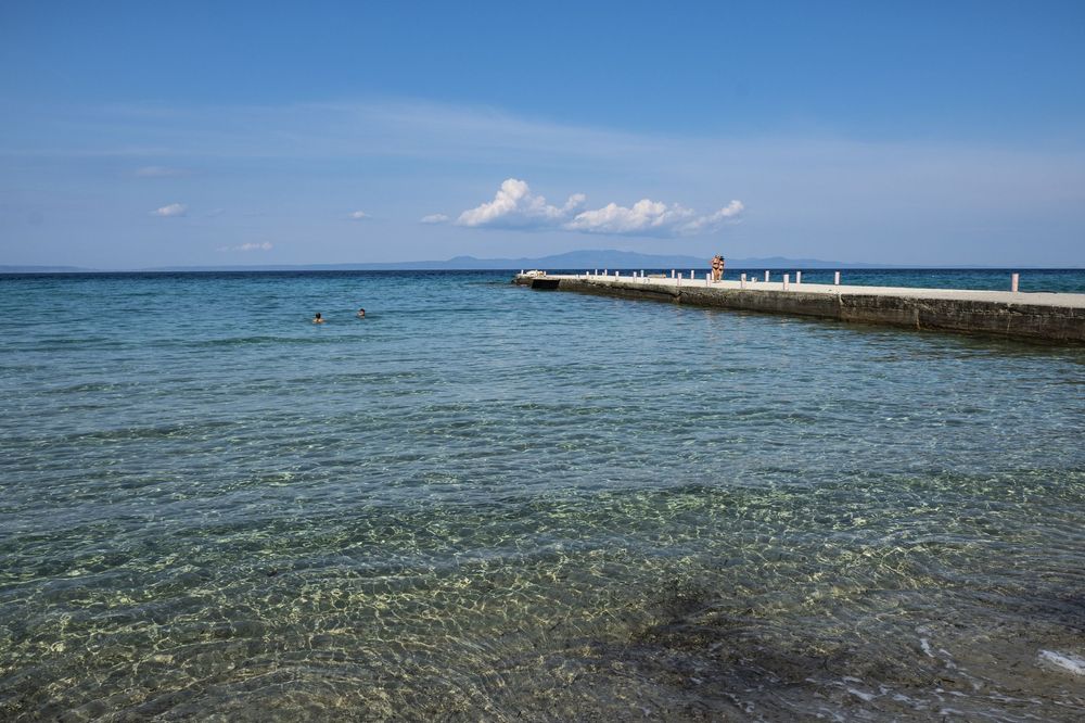 Panoramic view of a tropical beach with crystal clear turquoise waters stretching along the coastline.