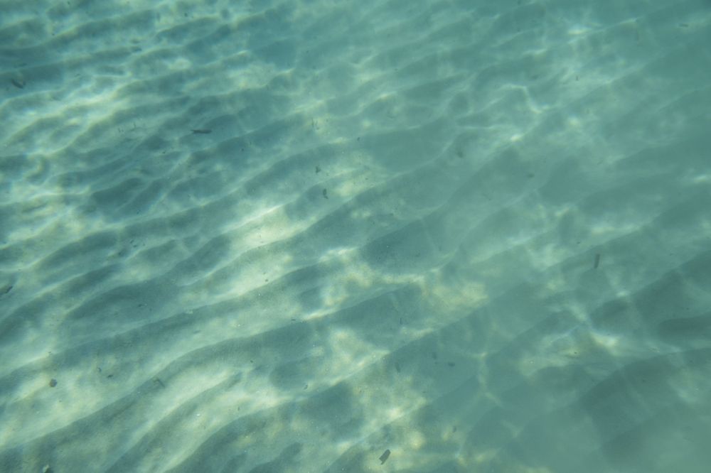 Turquoise blue ocean water ripples with sunlight creating a mesmerizing pattern beneath the surface.