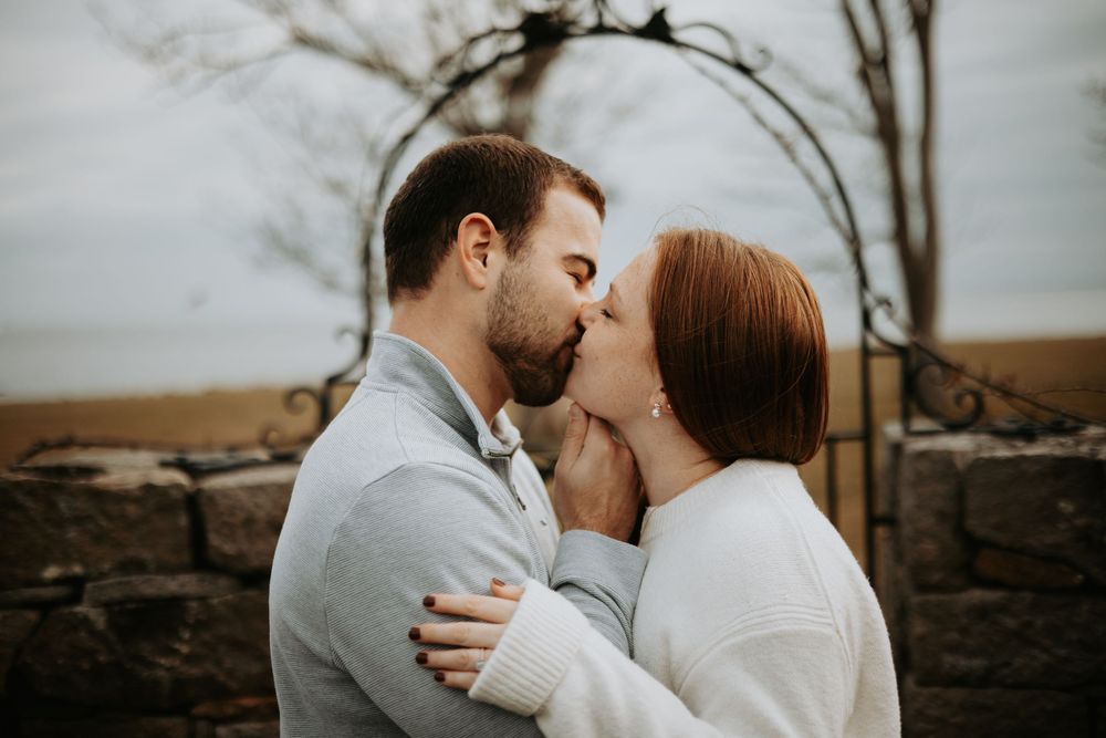 A romantic couple embraces in a tender moment against a moody winter landscape.