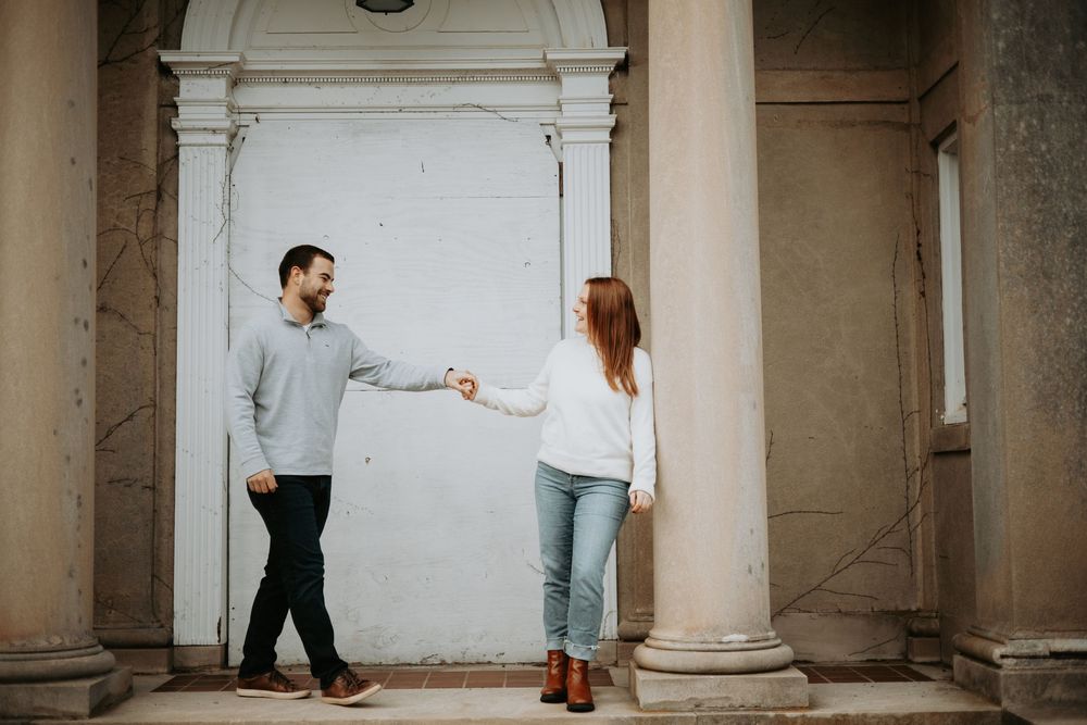 A couple dances together in an elegant stone colonnade hallway with classical architecture.