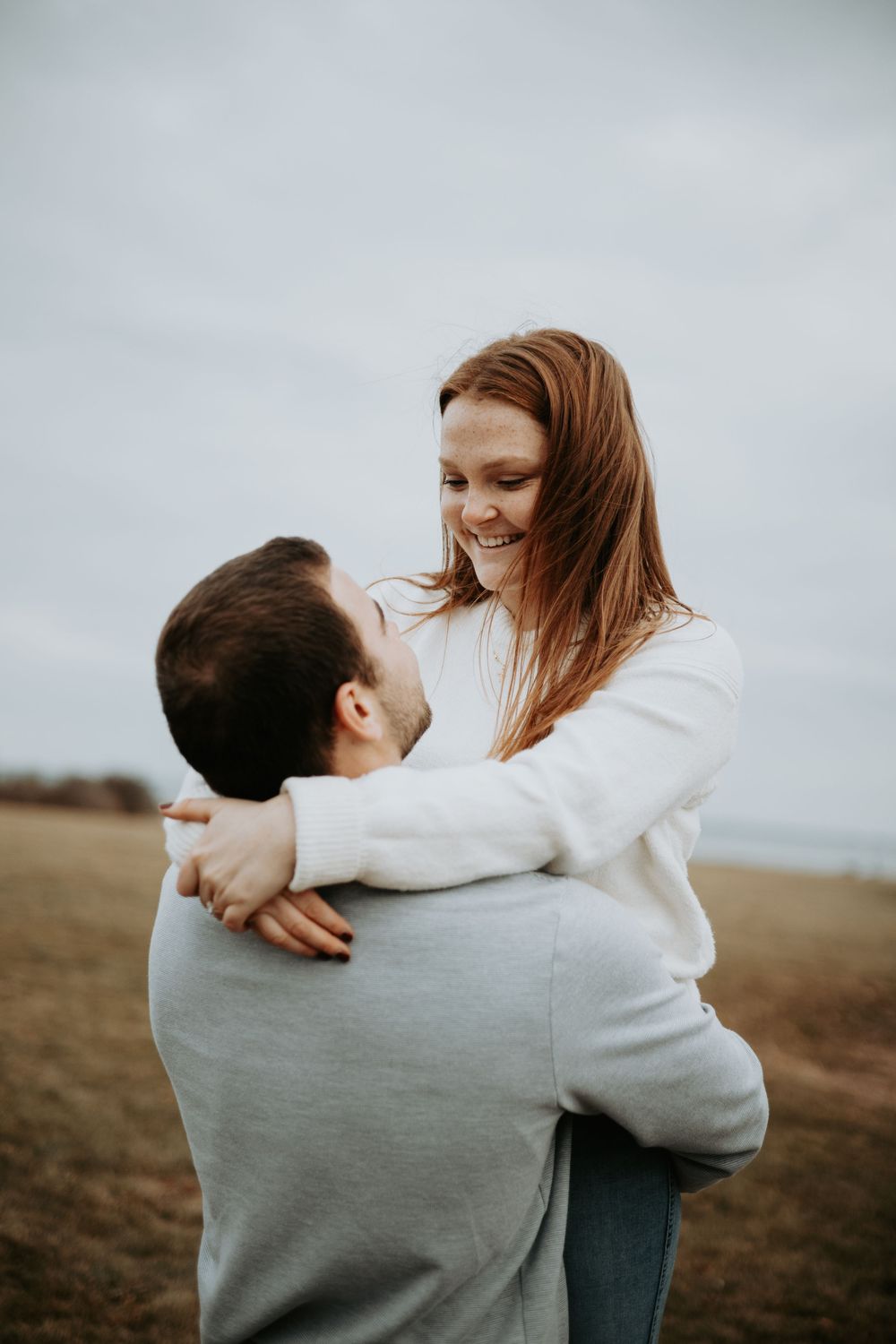 A couple in matching light sweaters share intimate embraces in a series of romantic outdoor photos.