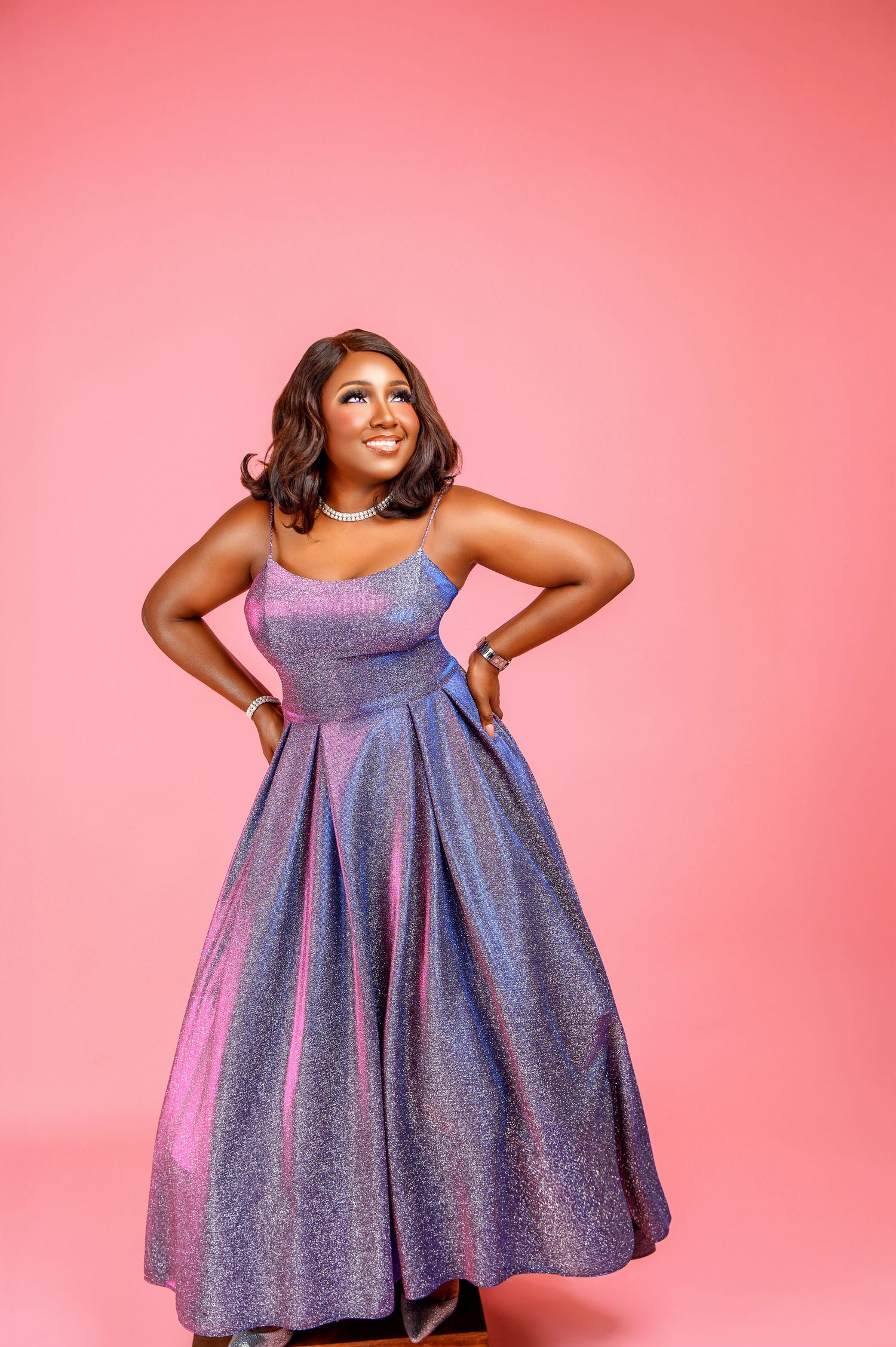 Model wearing a sparkly purple fit and flare party dress poses against pink background in four different angles.