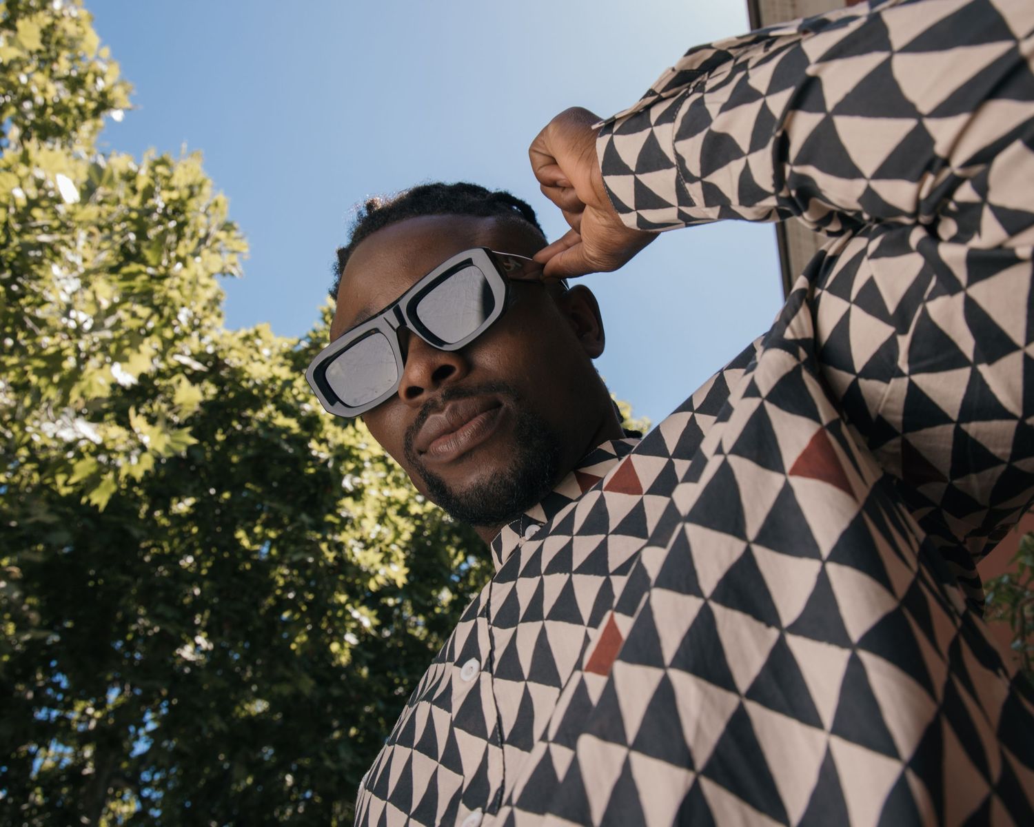 Fashion series with geometric pattern clothing shot against blue sky and trees.