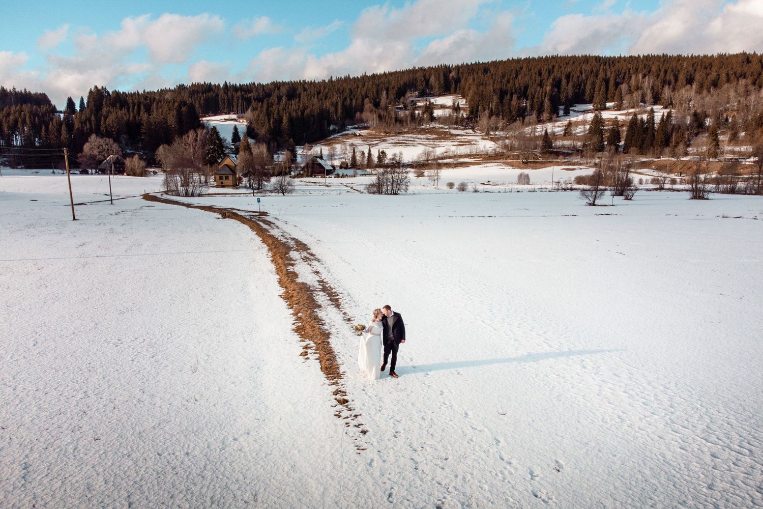 Spektakuläre Drohnenaufnahme eines Brautpaars in der verschneiten Schwarzwald-Landschaft, authentische Winterhochzeit ohne Kitsch.