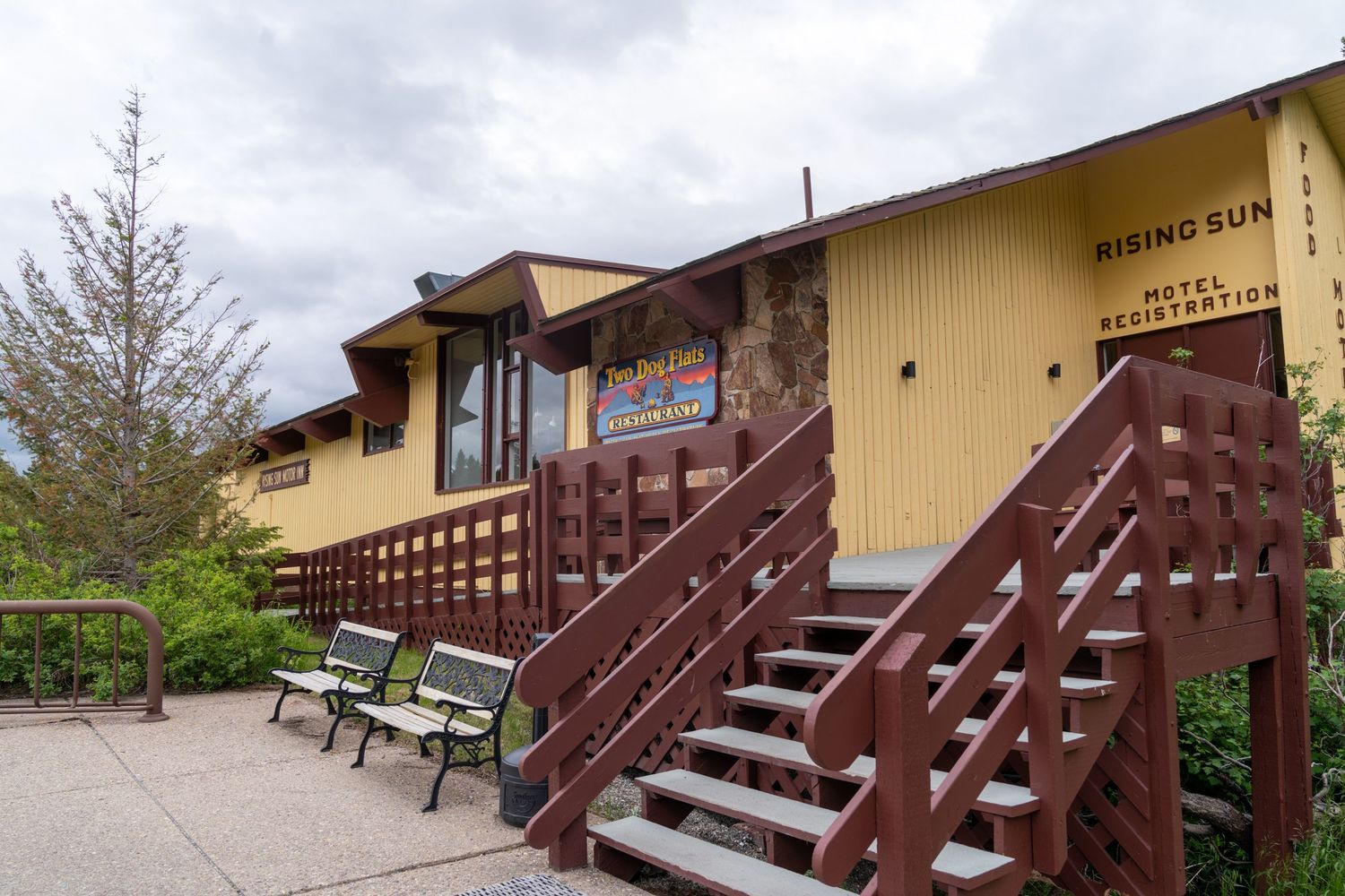 A series of brown wooden staircases and walkways leading to yellow buildings against a cloudy sky.