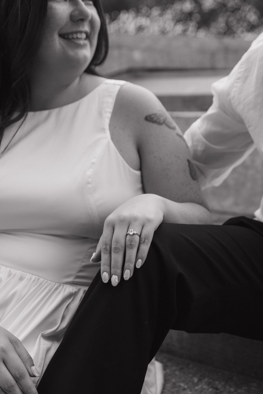 Black and white close-up of hands resting together showing an engagement ring.
