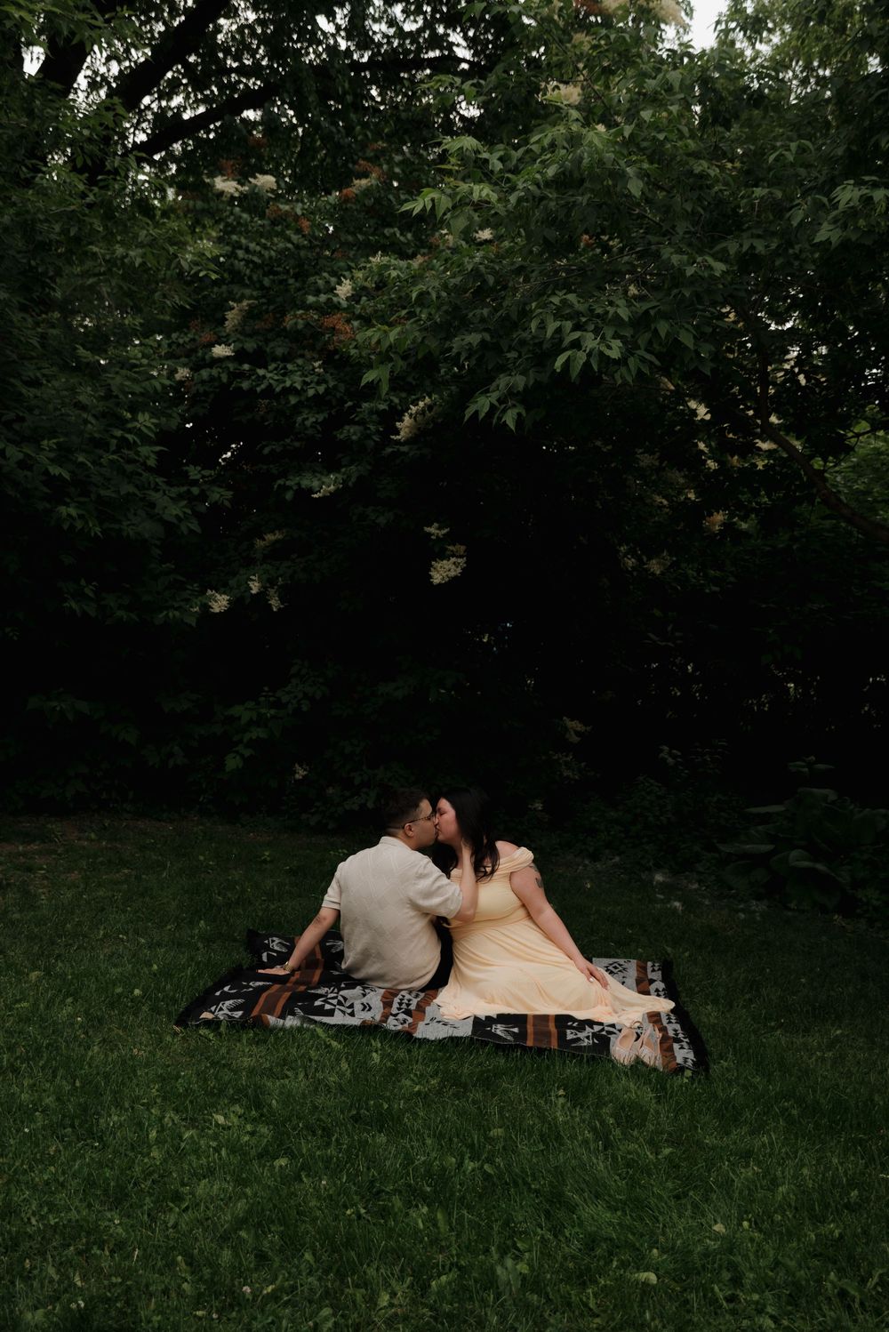 Two people relax together on a blanket in a serene garden setting.