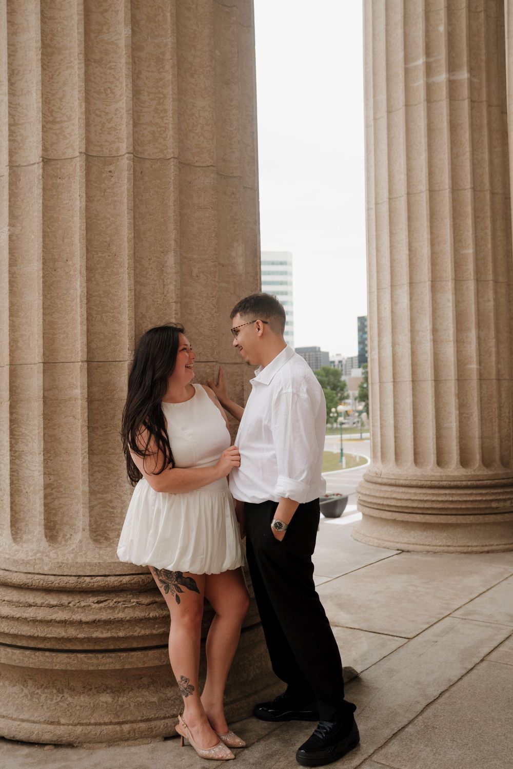 A romantic couple poses between classic stone columns in a series of intimate engagement photos.