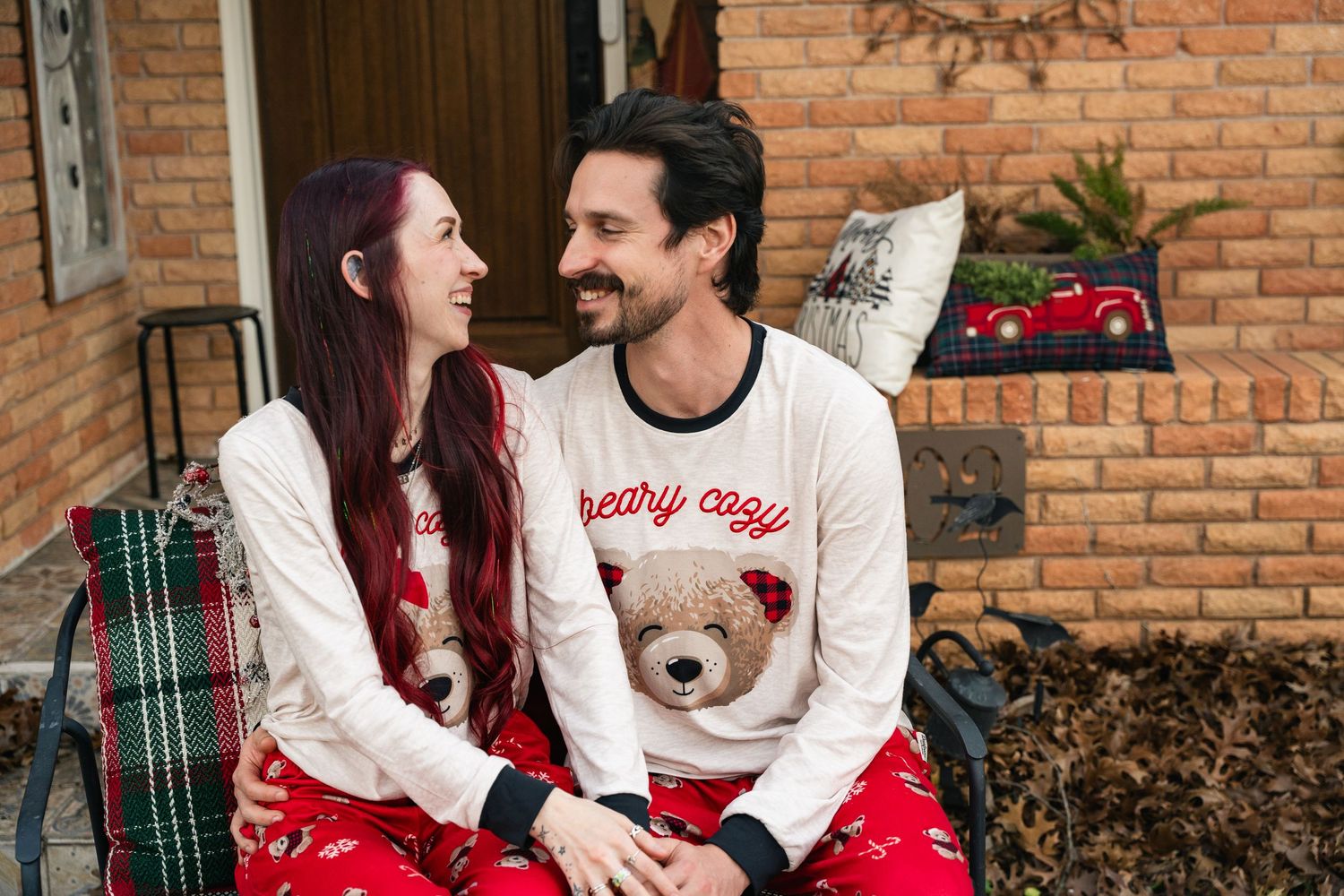 Young couple wearing Christmas pajamas smiling at each other for family photos in Fort Worth, Texas.