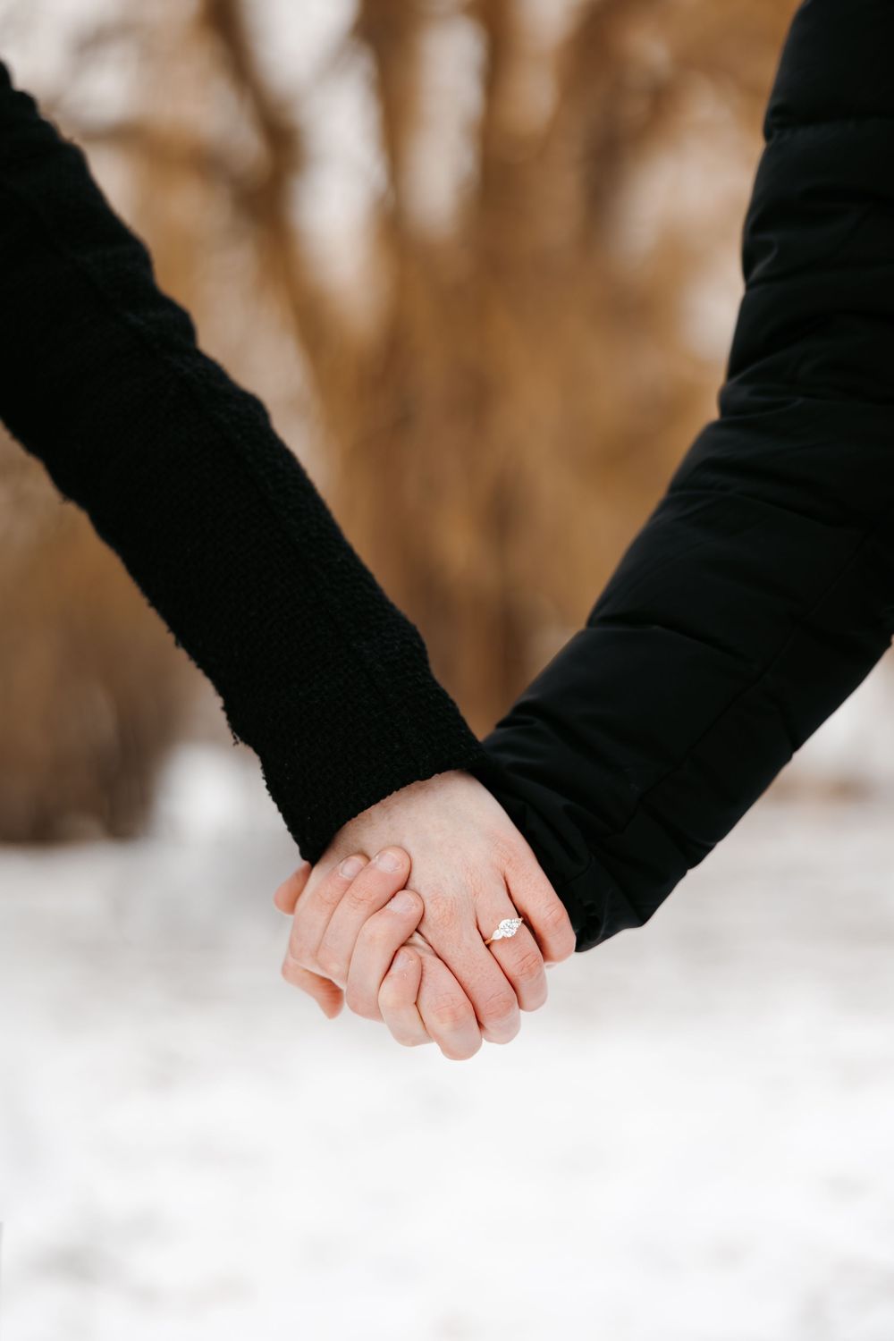 Close-up of two hands clasped together against a snowy winter background.